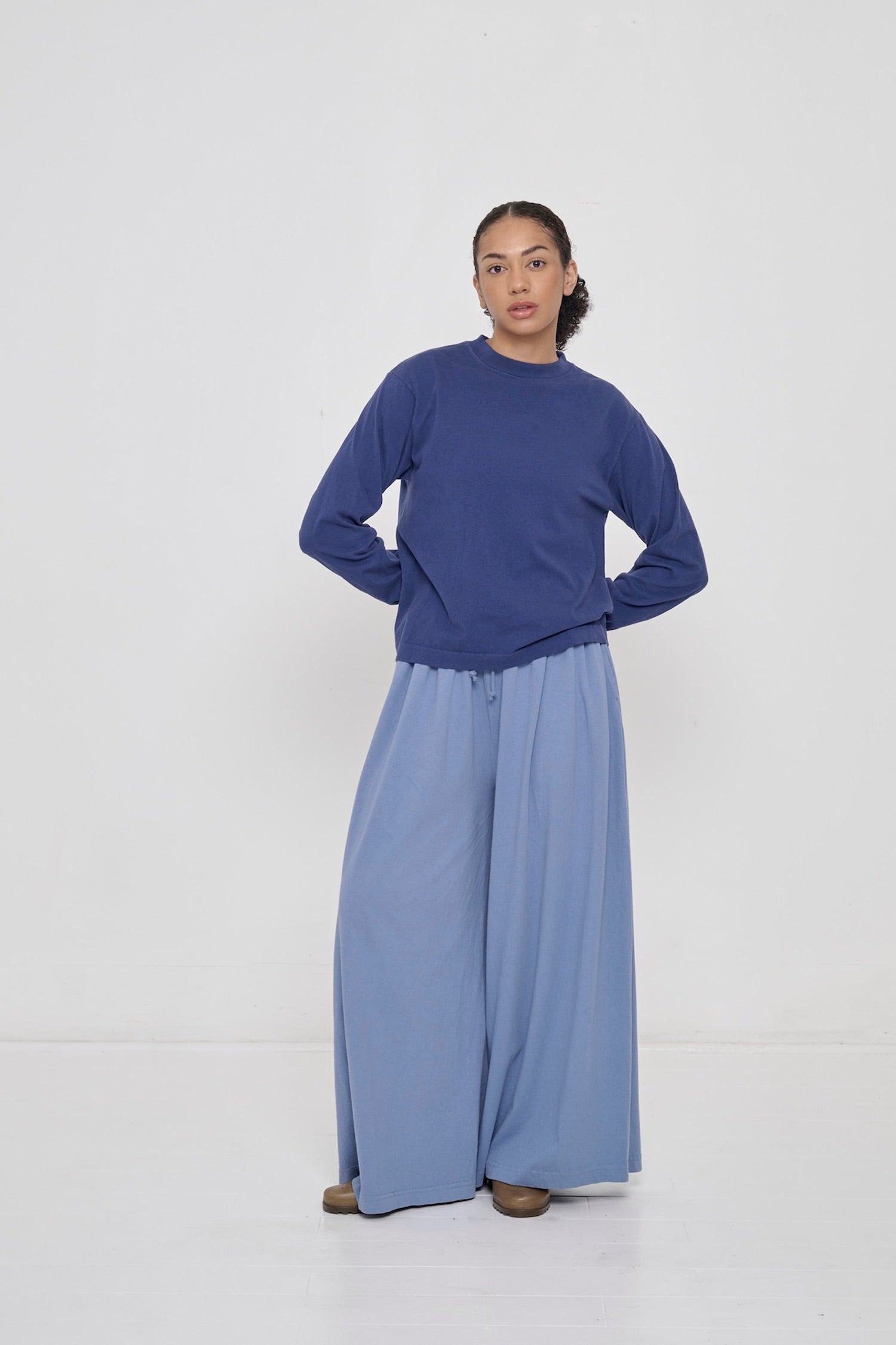 A person wearing Washed Navy Long Sleeve Boxier Trash Tee with Periwinkle Tubular Pants and clogs.