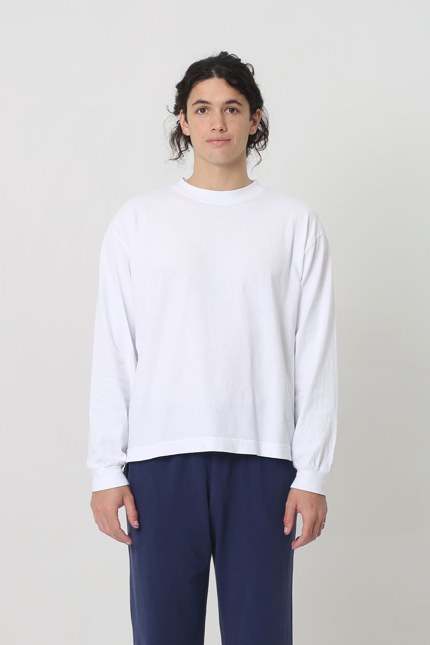 A 6' person in a size M White Long Sleeve Boxier Trash Tee. Hem hits their middle hip. 