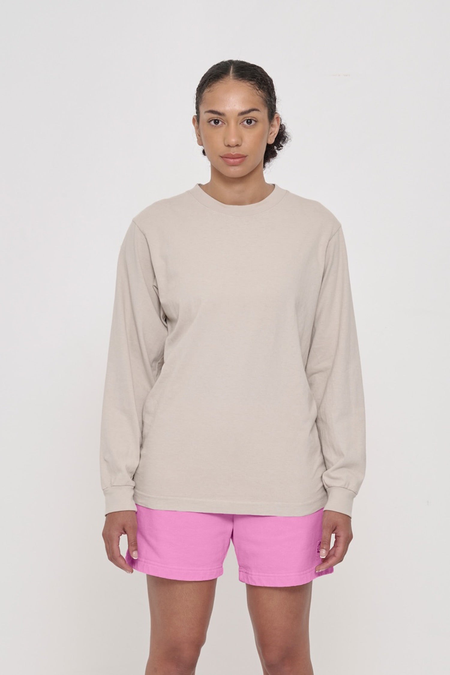  A woman wearing an Oat Long Sleeve Trash Tee. Shirt hem hits just below the hip. 