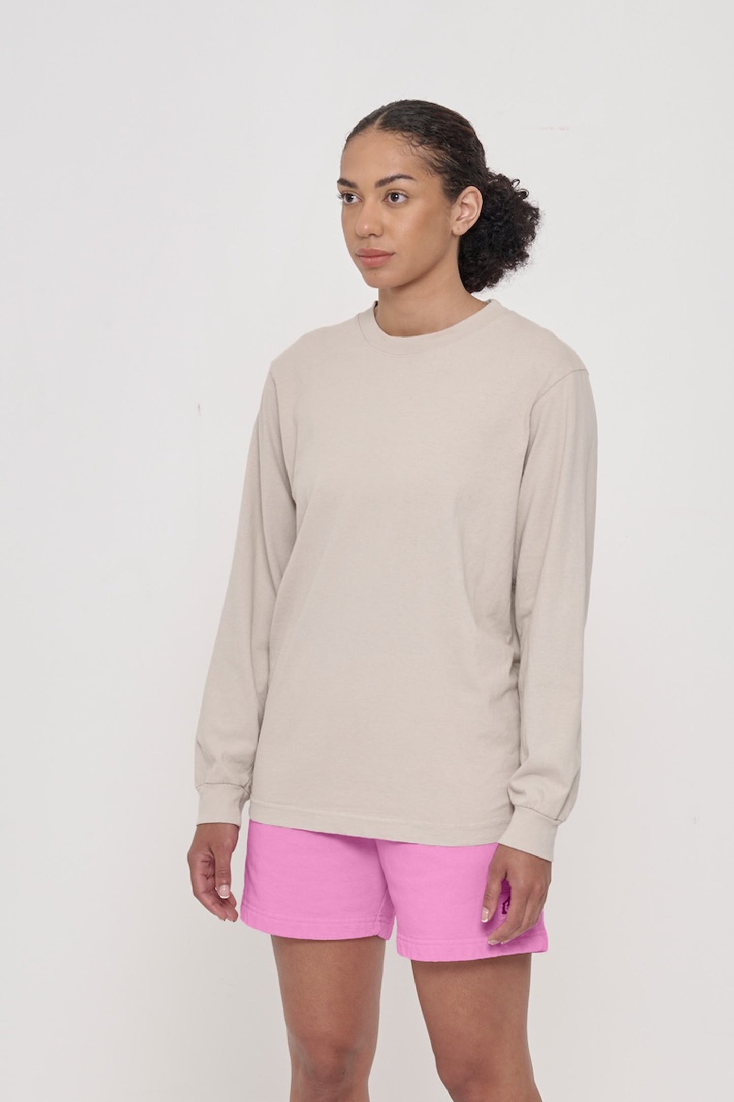 A person turned 45-degrees from the front, in an Oat Long Sleeve Boxier Trash Tee, shows the relaxed sleeves and rib cuff.