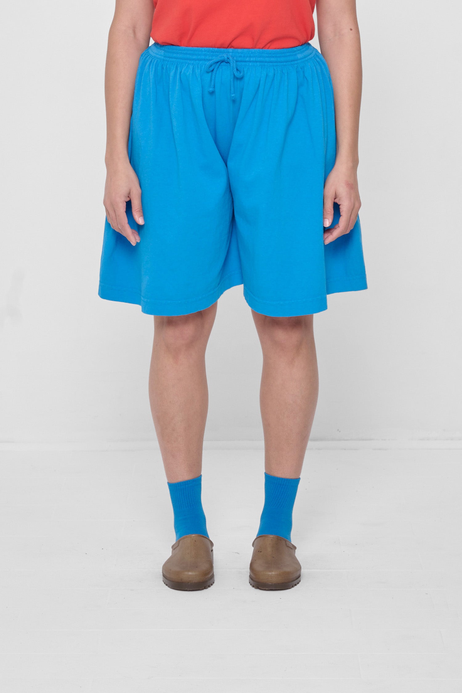 A 5'4" person in Low Rise Malibu Long Tubular Shorts. Hem ends at the knee.