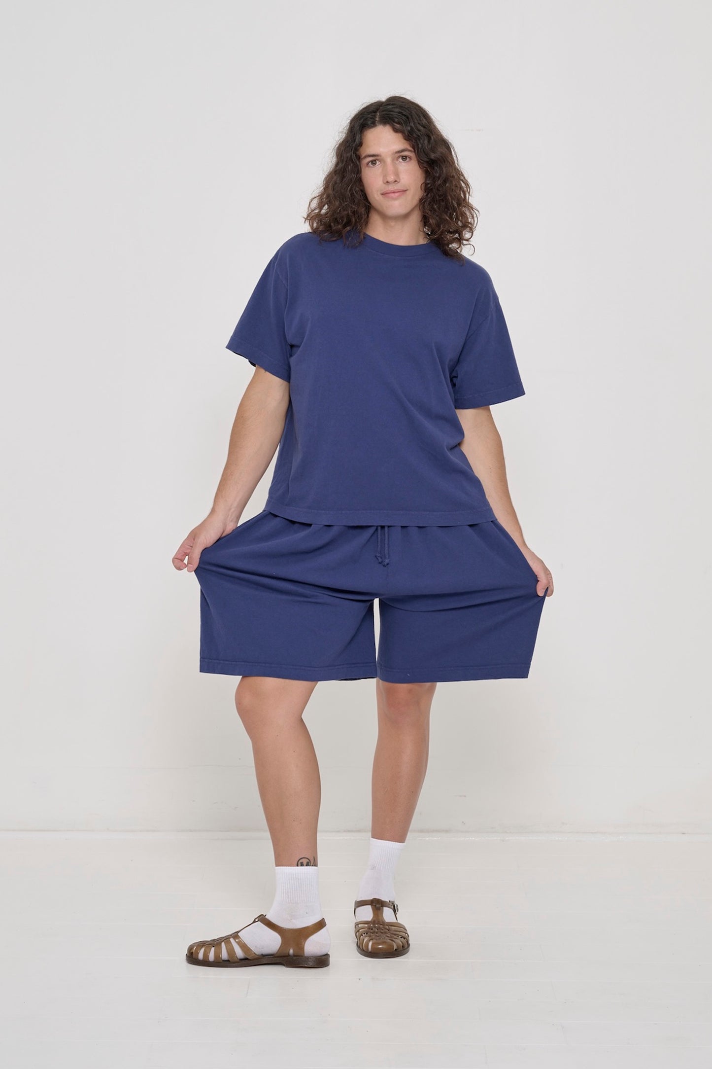 A person in Washed Navy Long Tubular Shorts with a Washed Navy Boxier Trash Tee. 