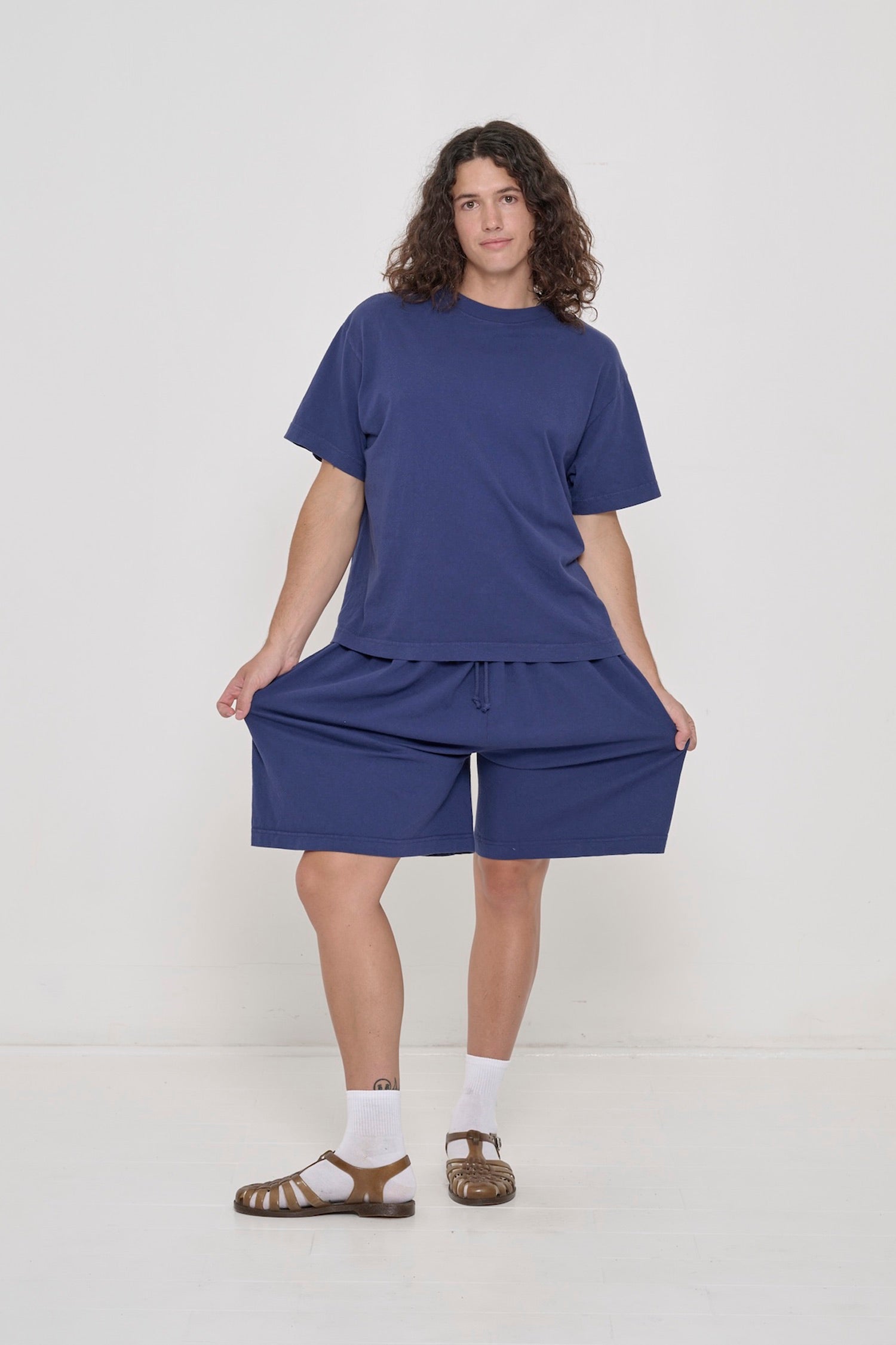 A person in Washed Navy Long Tubular Shorts with a Washed Navy Boxier Trash Tee. 