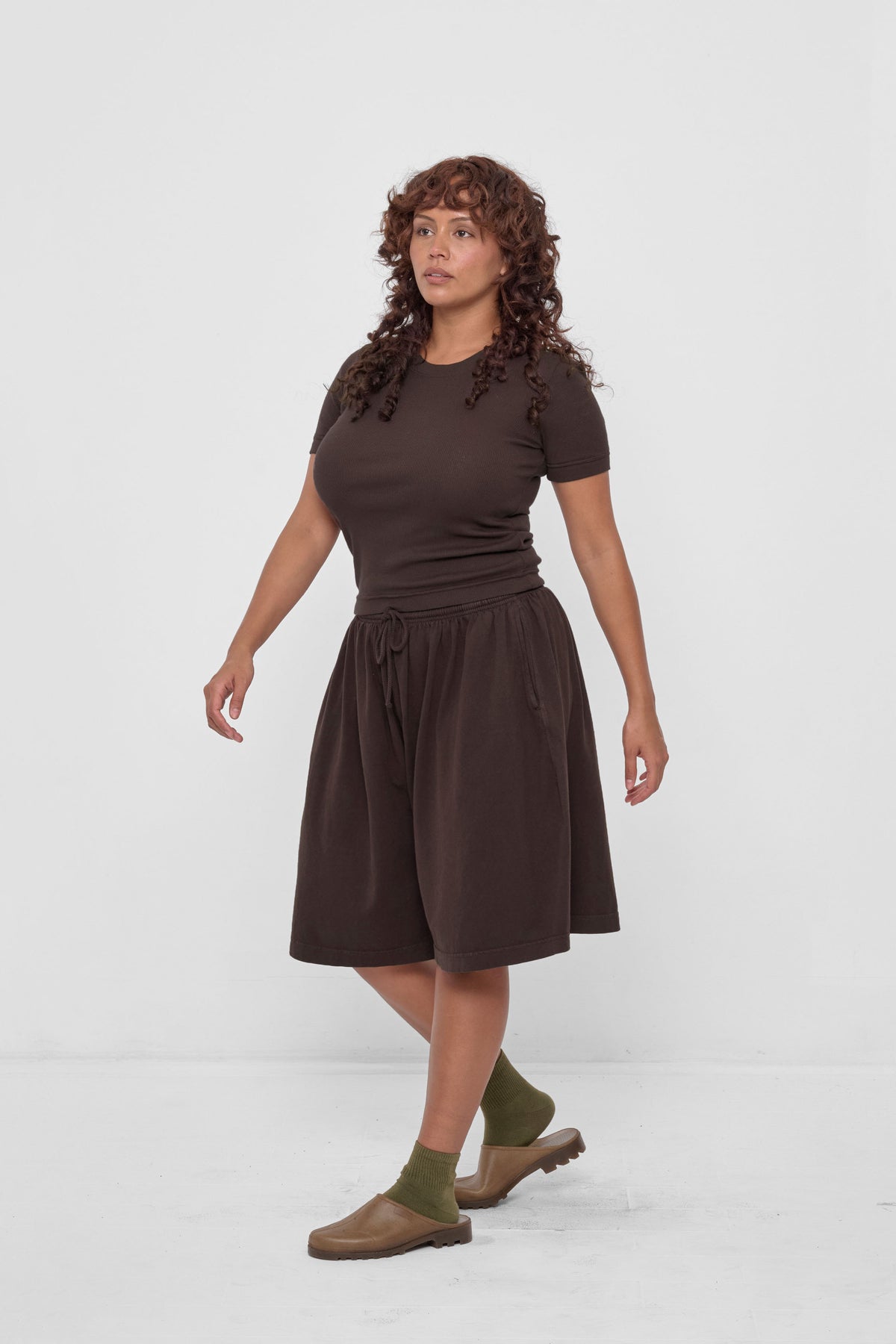 Long Tubular Shorts in Wet Soil – 3/4 view, styled with matching Rib Short Sleeve, Olive Spring Socks and Plasticana Mules