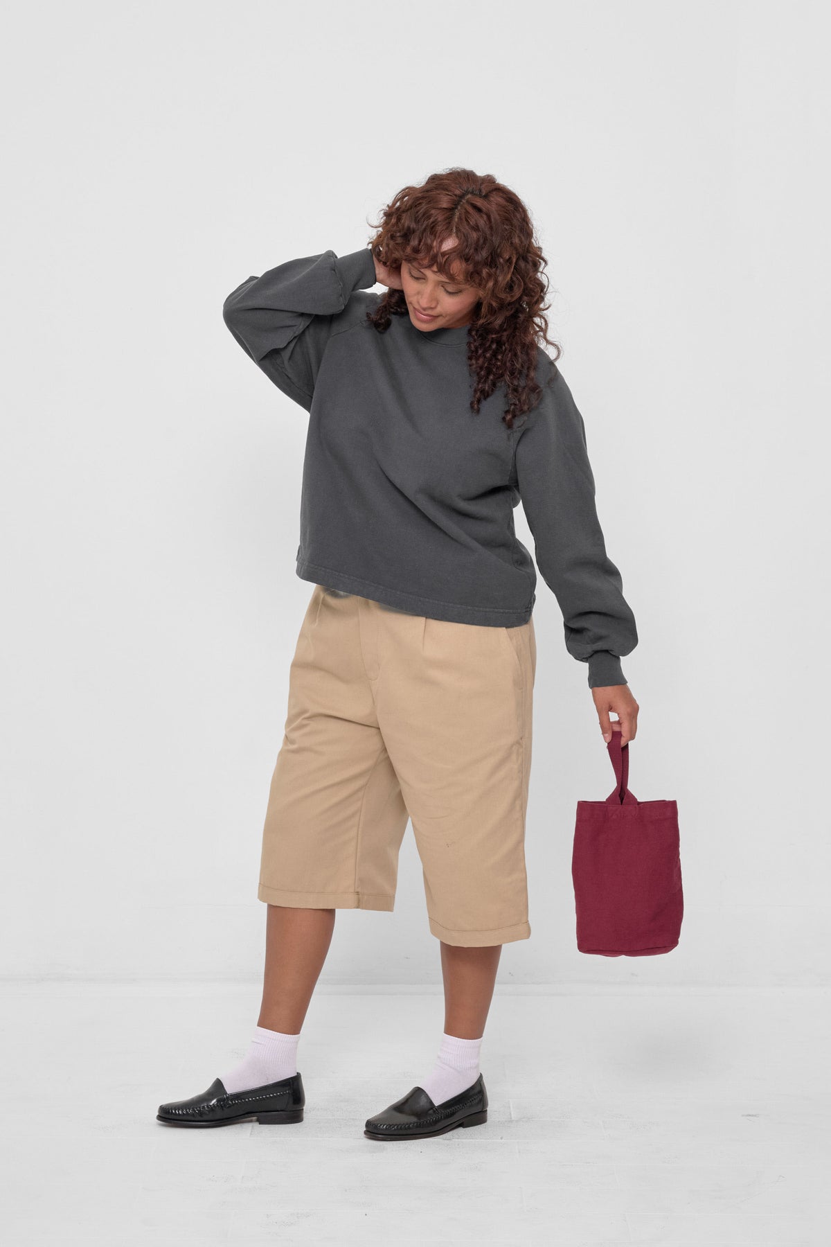 Loop Tote in Garnet – Model wearing a Slate Trash Raglan holds the tote in her hand for scale