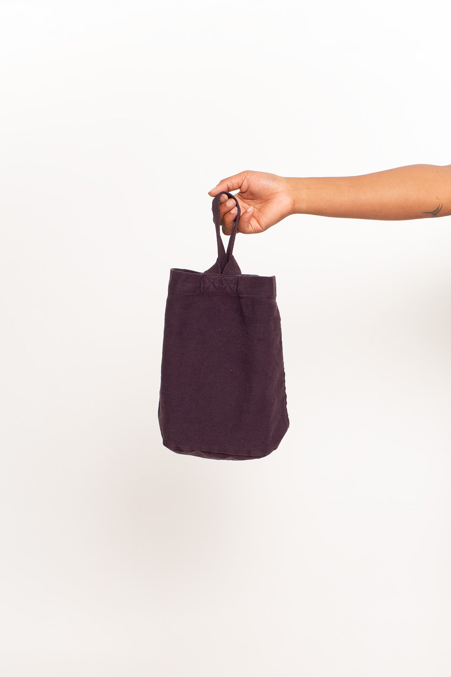 Mulberry Loop Tote, with longer strap facing the front, held in a person's hand, shows gussets, depth, stitching.