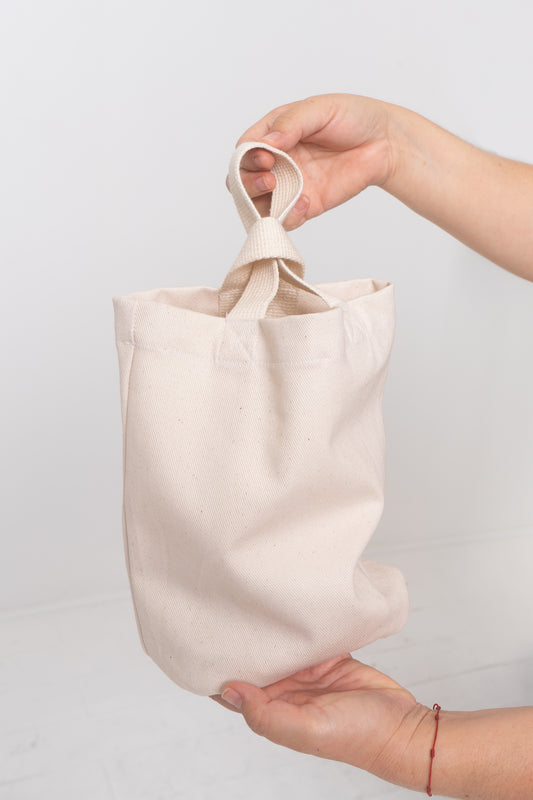 Loop Tote in Natural, held in a person's two hands, showing fabric texture and stitching.