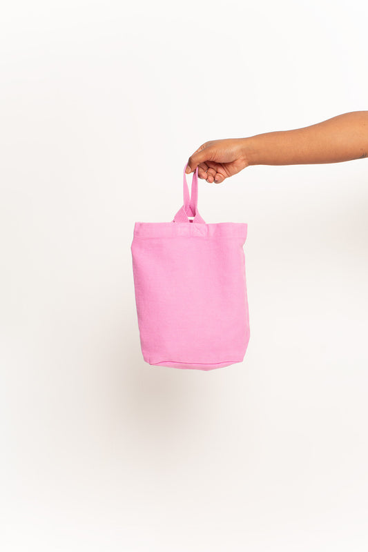 Pixie Loop Tote, with longer strap facing the front, held in a person's hand, shows gussets, depth, stitching.