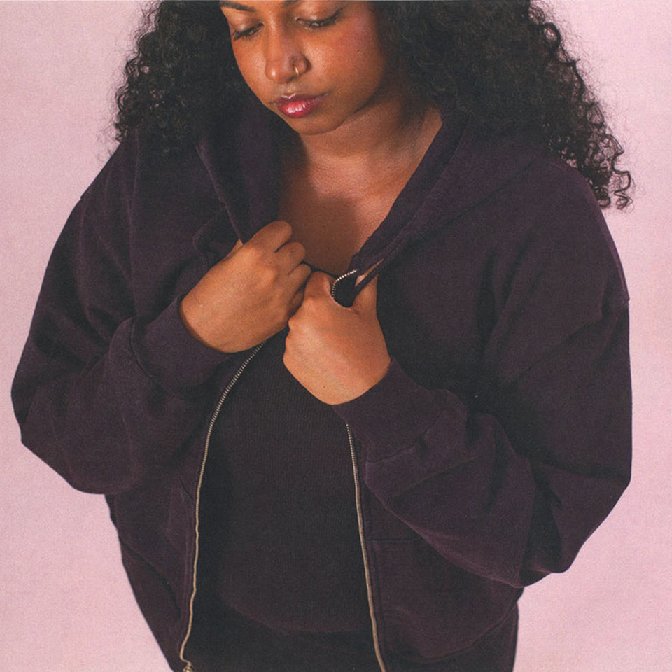 Person wearing a Zip Up Trash Hoodie in Mulberry against a light pink background