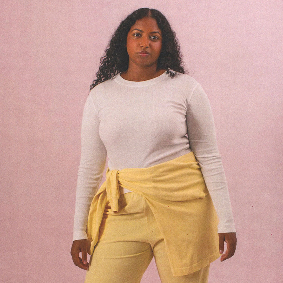 Woman wearing a Rib Long Sleeve in White with French Butter Apartment Pants and a Boxier Long Sleeve Tied around her waist.