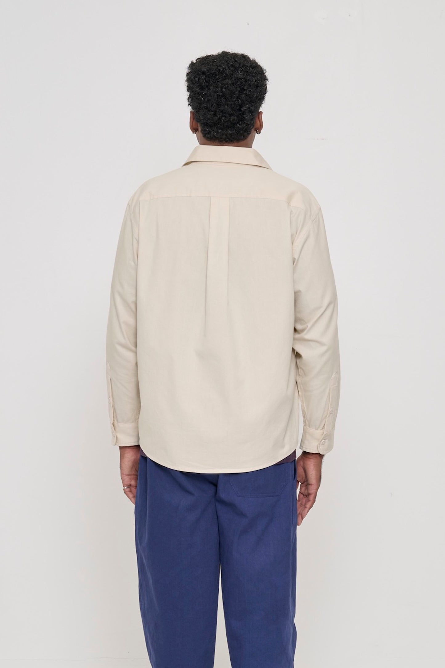 Back view: A person in an Oat Peach Fuzz Twill Button Up Shirt. Shows the box pleat at yoke.