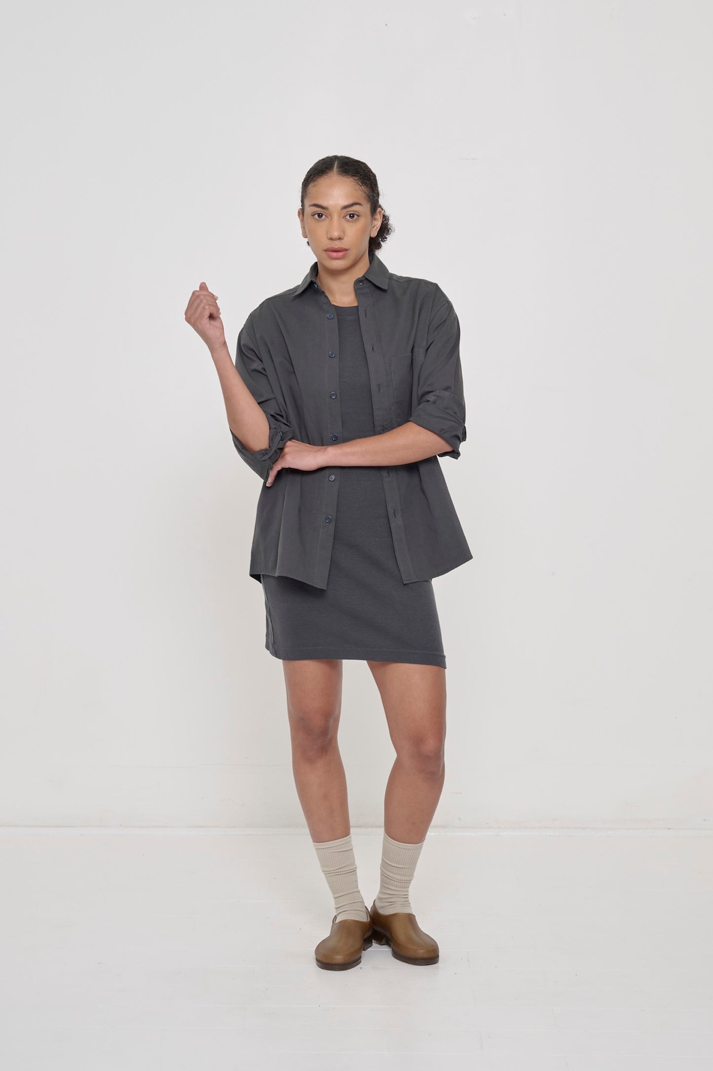 A person in a Slate Peach Fuzz Twill Button Up Shirt. Paired with a Rib Dress, Squishy Socks and Plasticana Gardana Clogs.