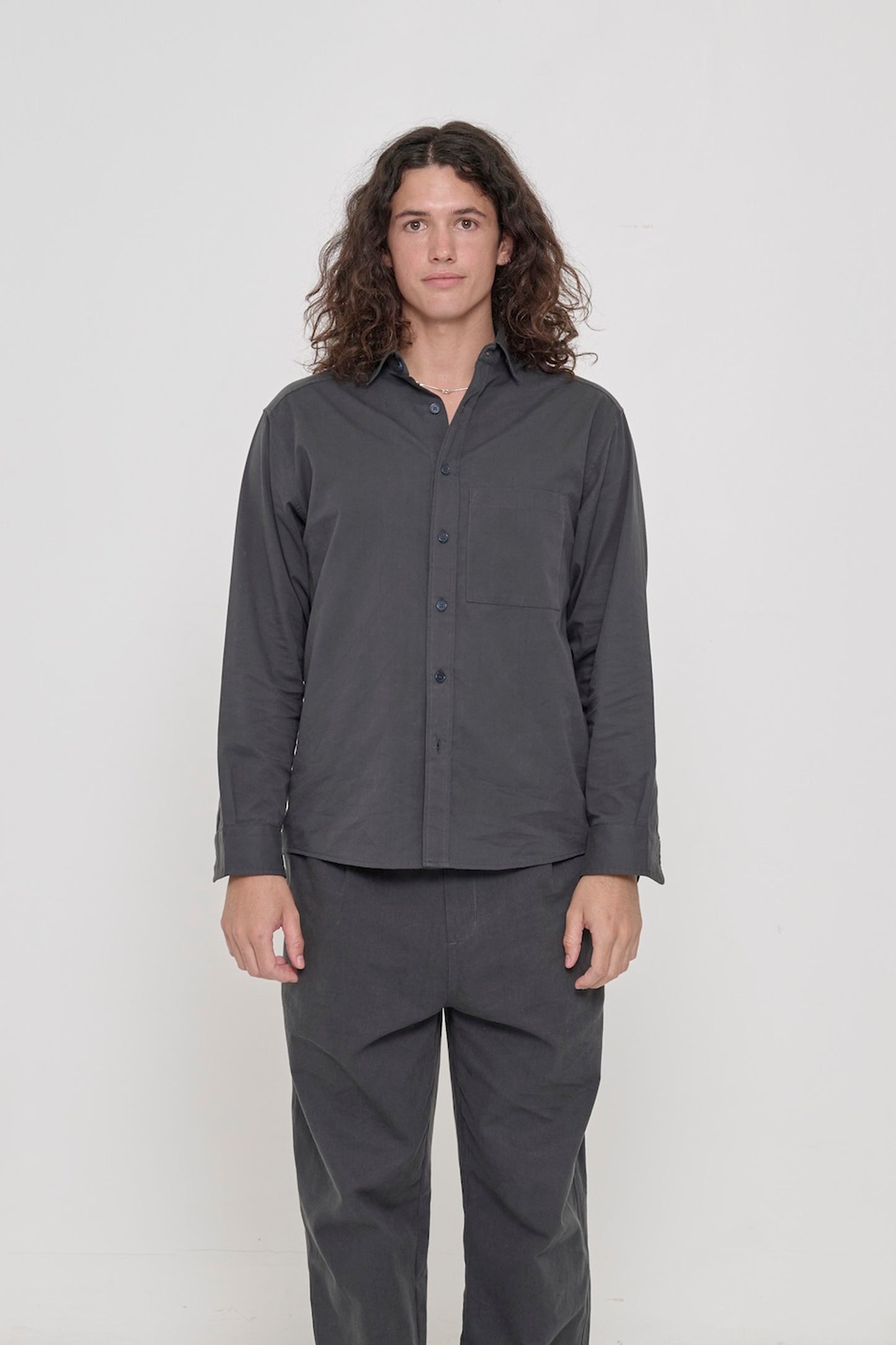 Person in a Slate Peach Fuzz Twill Button Up Shirt, buttoned up and worn with matching Cotton Twill Life Uniform Pants. 