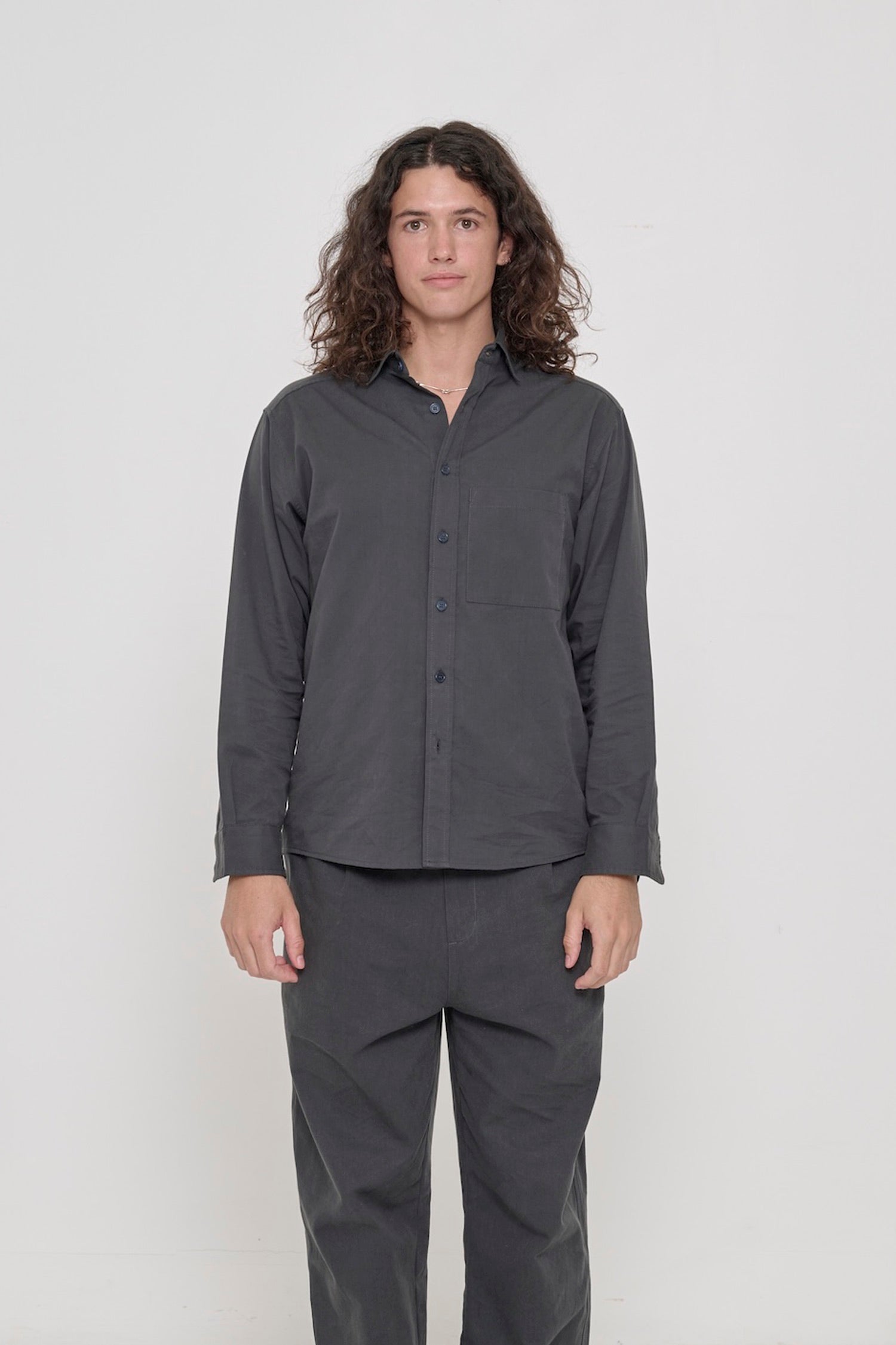 Person in a Slate Peach Fuzz Twill Button Up Shirt, buttoned up and worn with matching Cotton Twill Life Uniform Pants. 