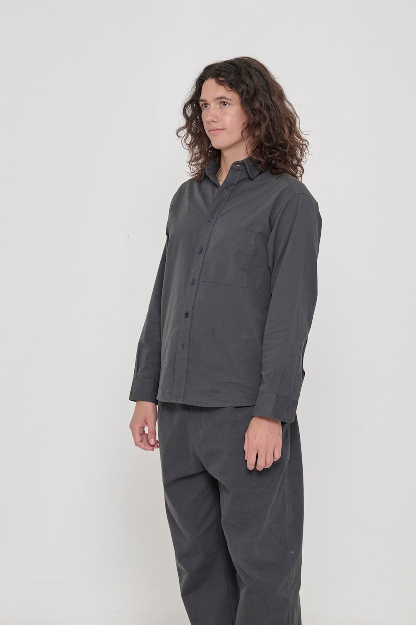 A person in a Slate Peach Fuzz Twill Button Up Shirt in a 3/4 front view, highlighting the shirt's sleeves. 