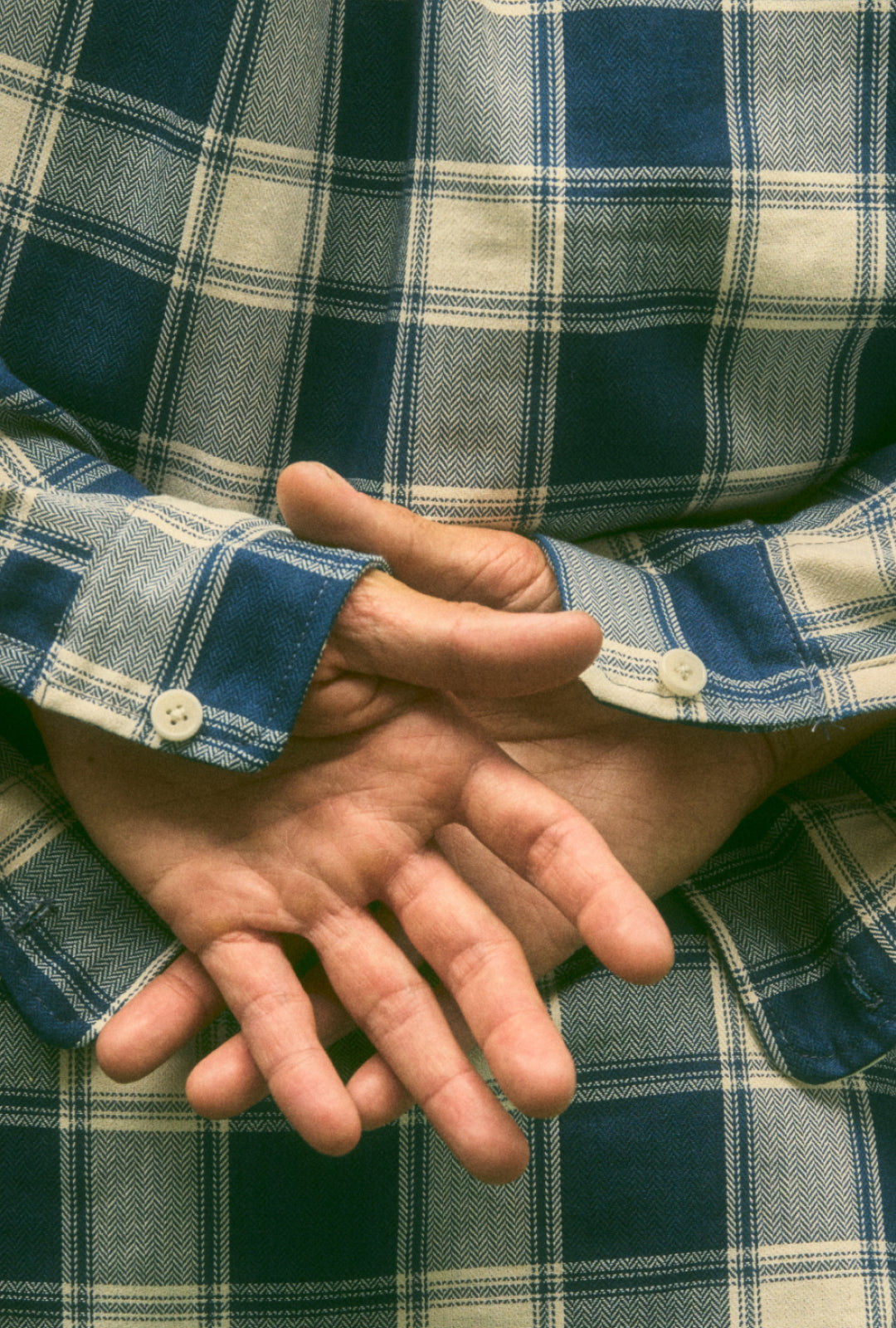 A model wearing a herringbone deadstock Plaid Button-Up Shirt with hands behind his back showing off the single button cuffs