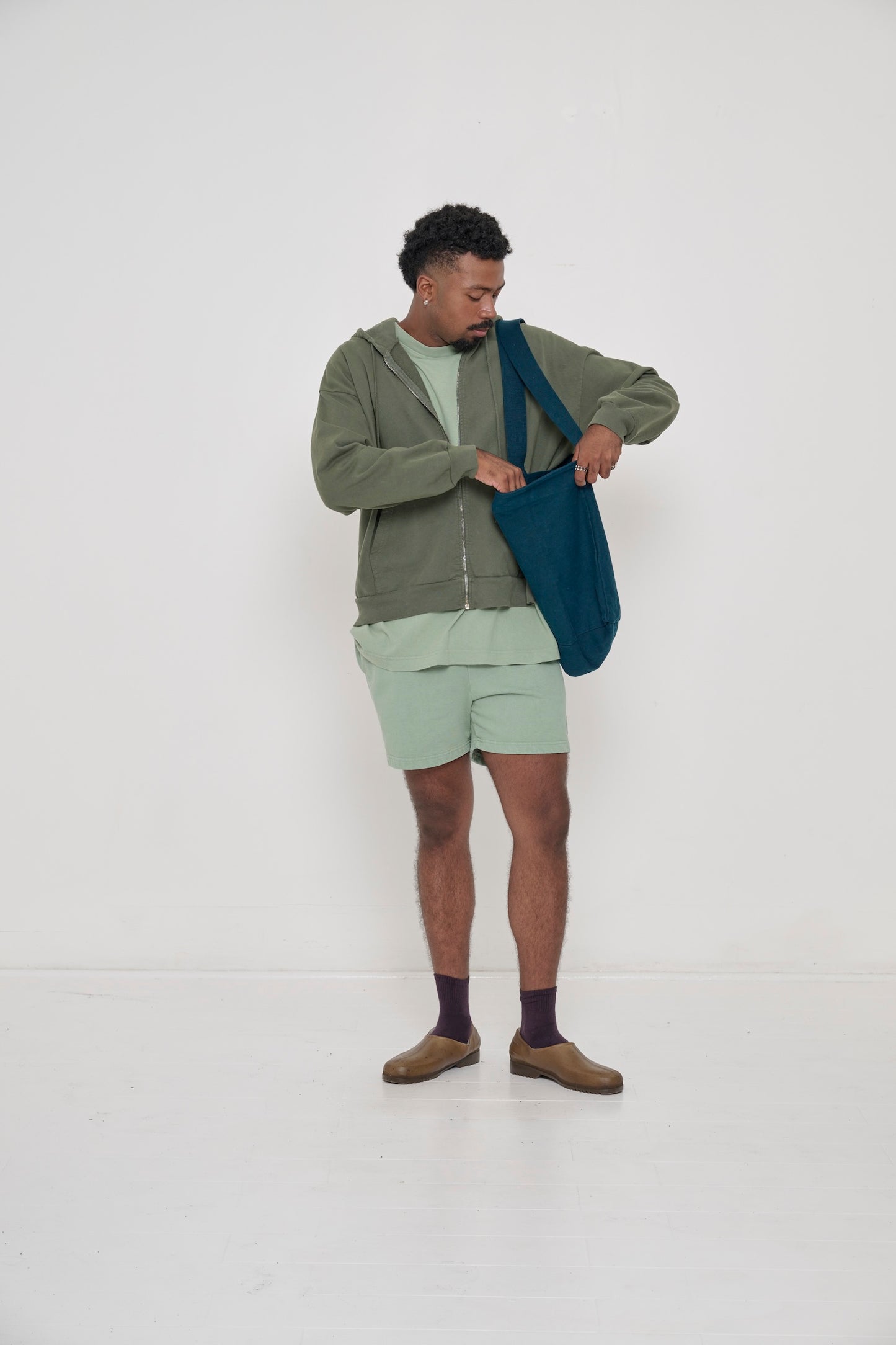 Model wearing Hemp Plasticana Gardana Clogs with Mulberry Squishy Socks and Wasabi Trash Fleece Everyday Shorts.