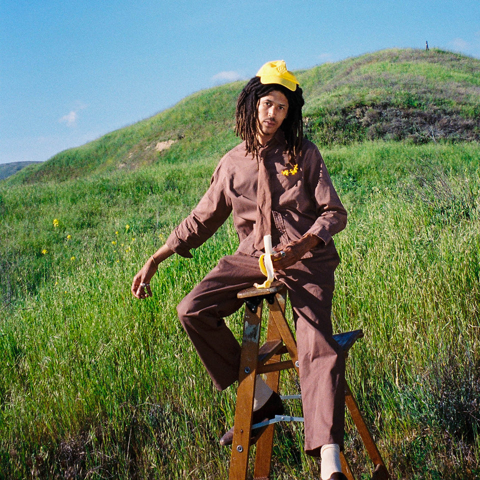 Man sitting on ladder wearing Potting Soil Button-Up Shirt, Tie, and Life Uniform Pants.
