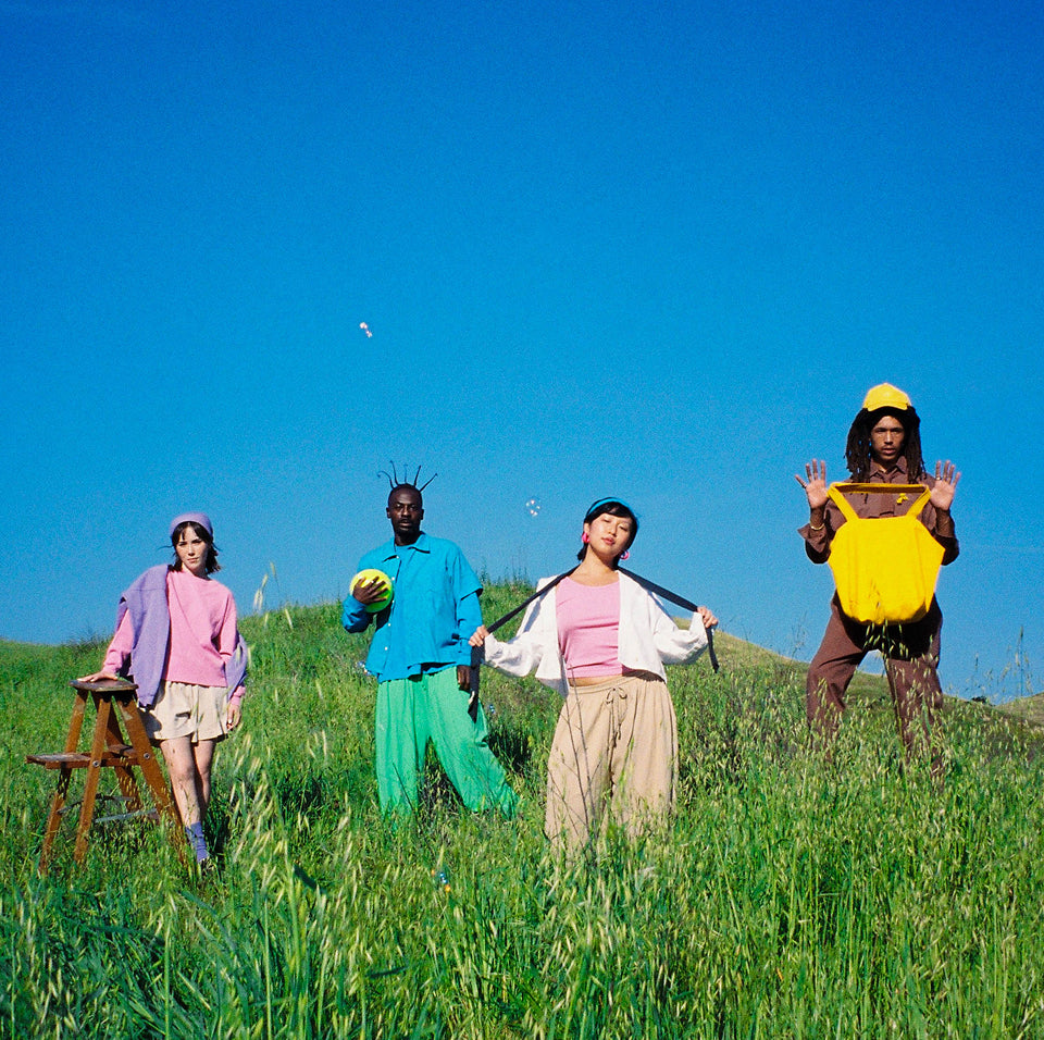 Group of four people in a field wearing clothing pieces from the new Wish Enjoyer collection.