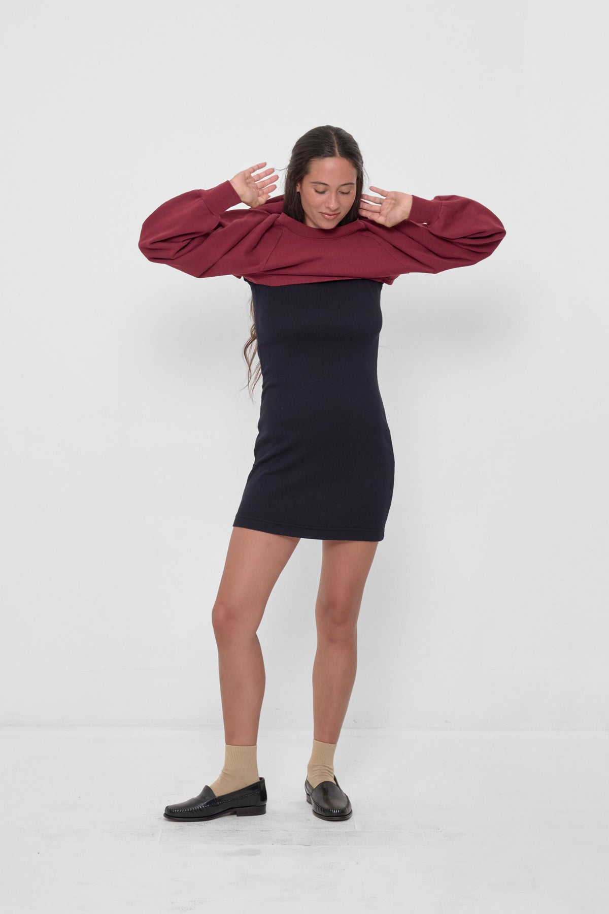 Rib Dress in Black – front full body view, with model putting on the Garnet Trash Crewneck