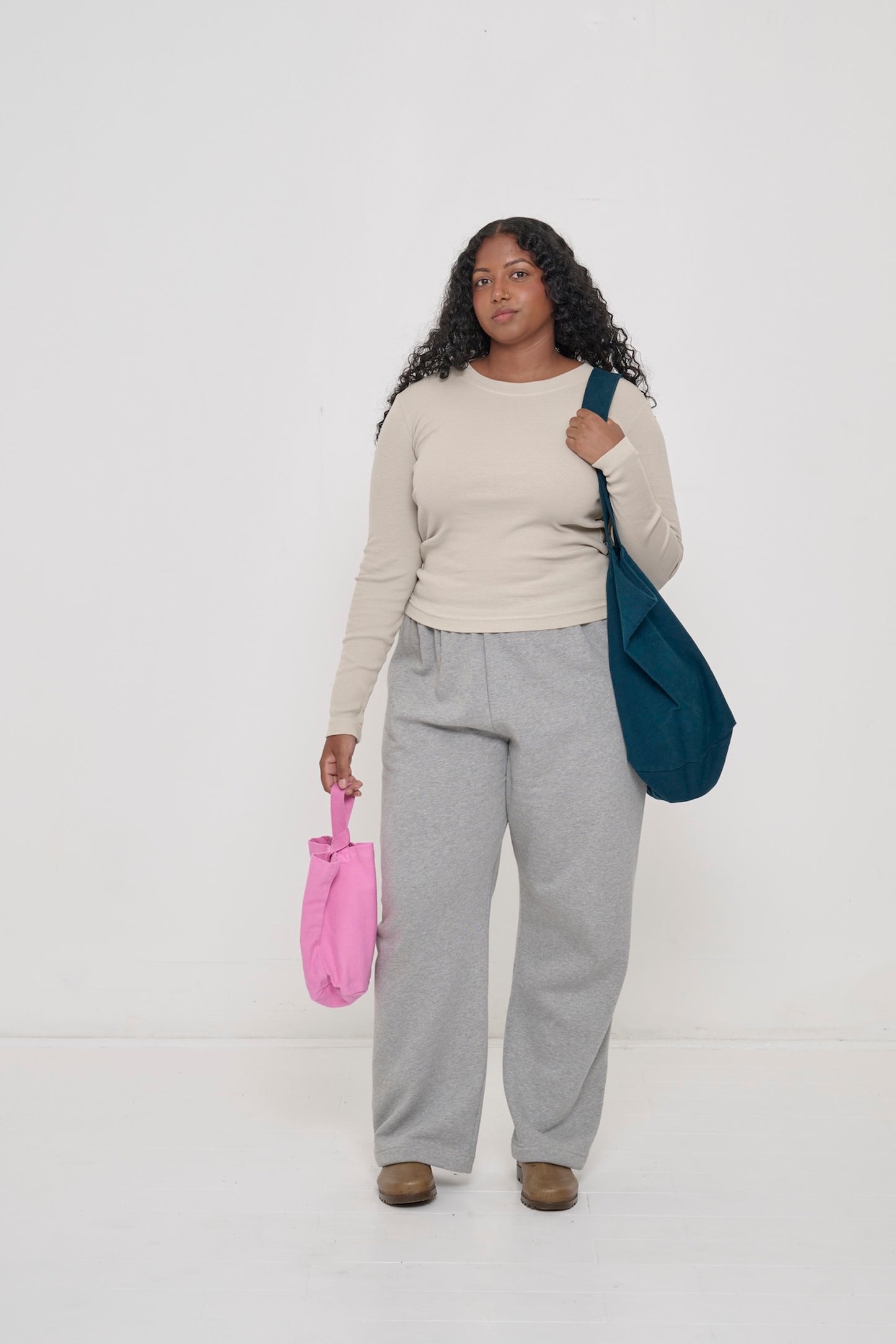 Woman wearing an Oat Rib Long Sleeve with Heather Sweatpants, holding a Loop Tote in one hand and a Big Tote over her shoulder.