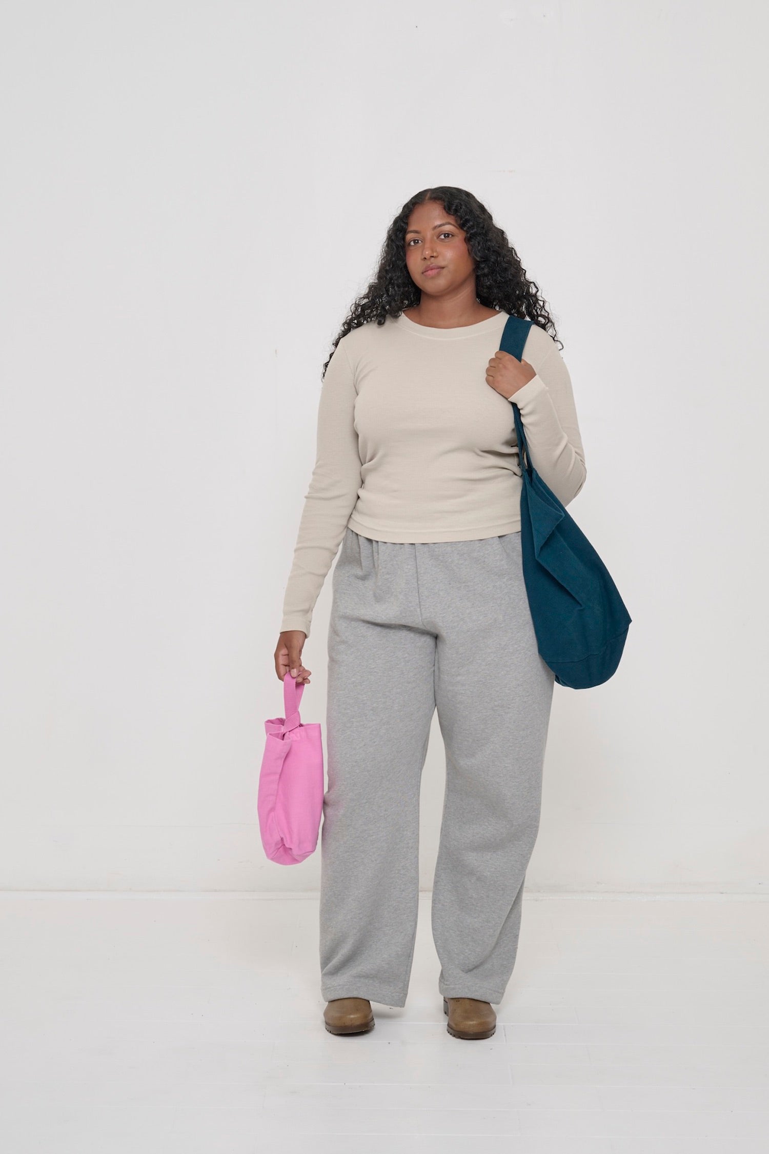 Woman wearing an Oat Rib Long Sleeve with Heather Sweatpants, holding a Loop Tote in one hand and a Big Tote over her shoulder.