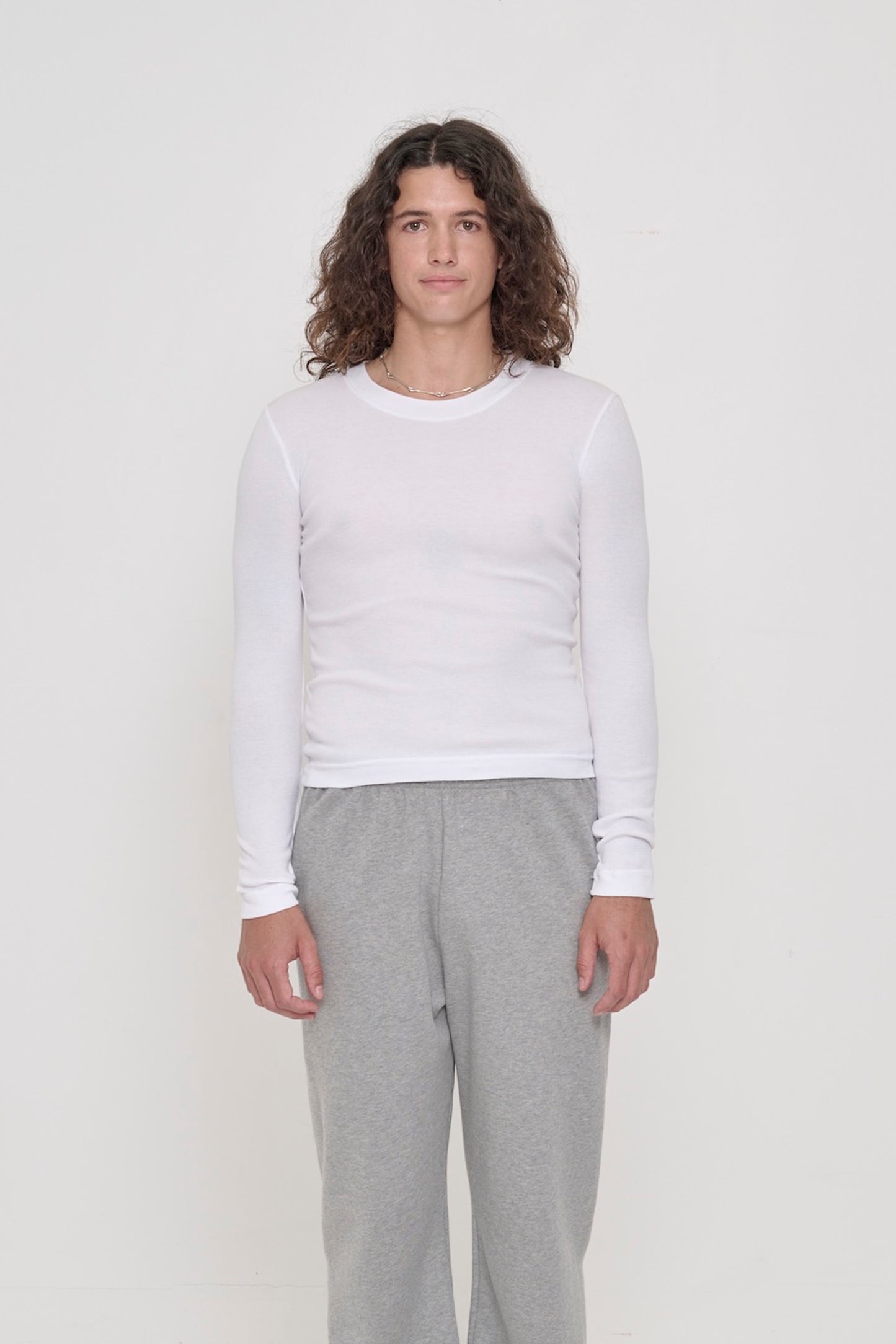 A 6' person in a size M Rib Long Sleeve in White. Heavy bottom hem hits the top of their hips.