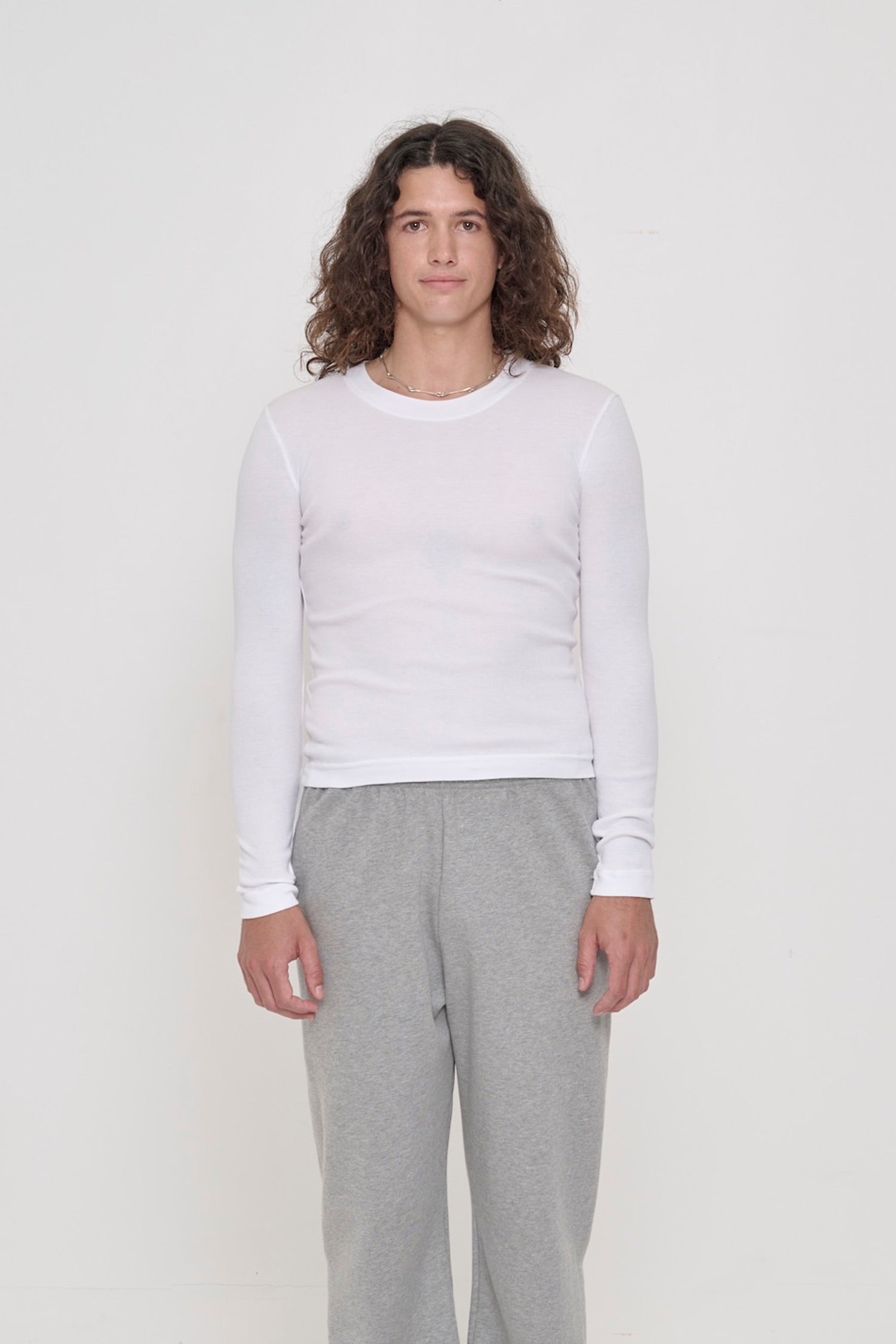 A 6' person in a size M Rib Long Sleeve in White. Heavy bottom hem hits the top of their hips.