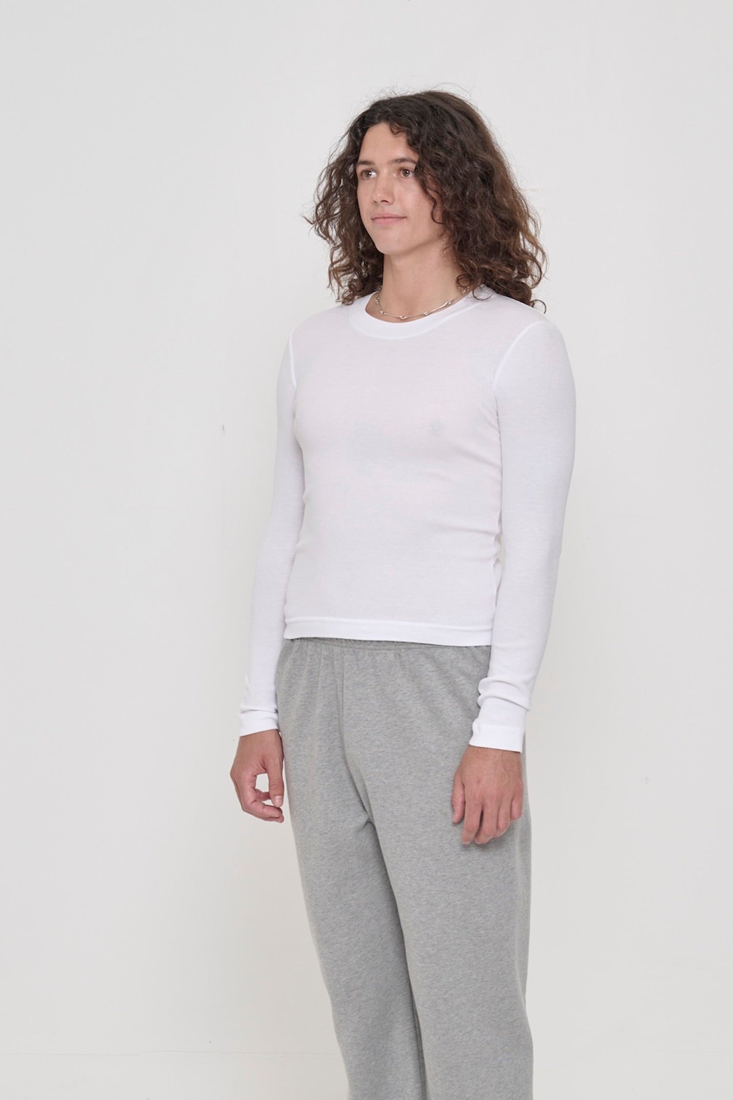 A person facing 45-degrees from the front, in a White Rib Long Sleeve, Shows side seams, heavy hem, and fitted silhouette.
