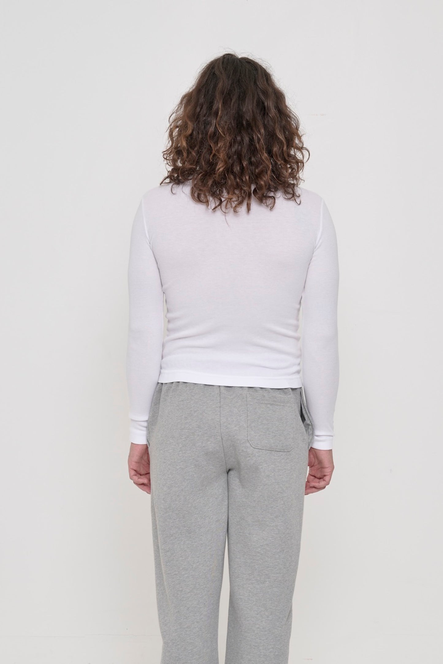 Back view: a person in a White Rib Long Sleeve. Fitted across the upper back with a little ease across the mid to lower back.