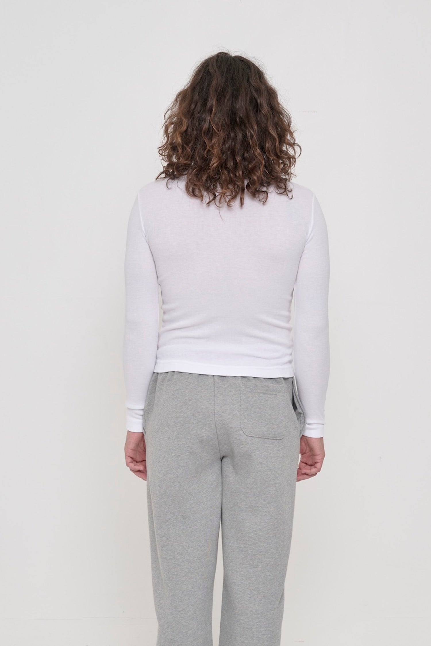 Back view: a person in a White Rib Long Sleeve. Fitted across the upper back with a little ease across the mid to lower back.