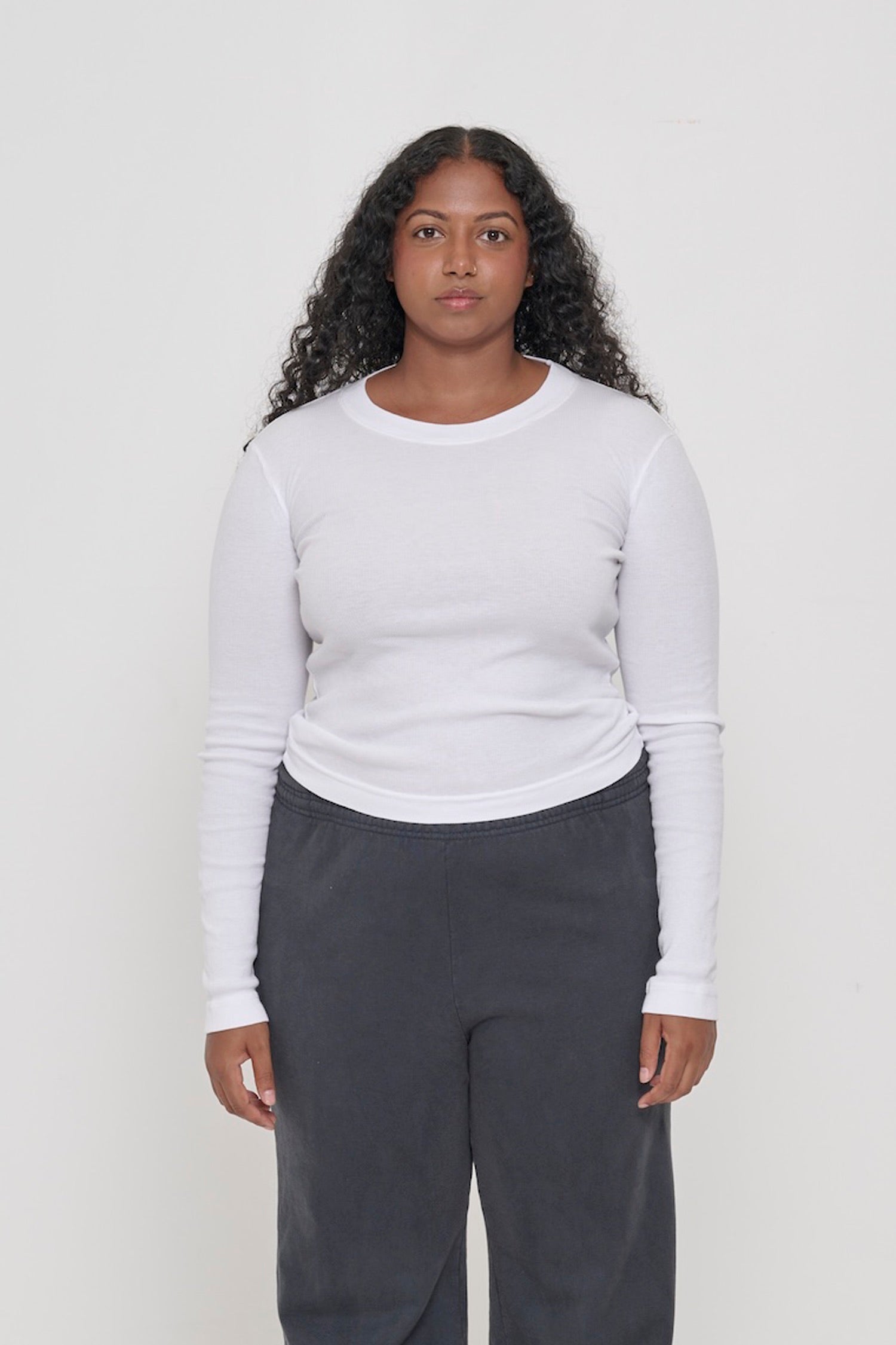 A 5'8" woman in a size M Rib Long Sleeve in White. Heavy bottom hem hits the top of her hips.