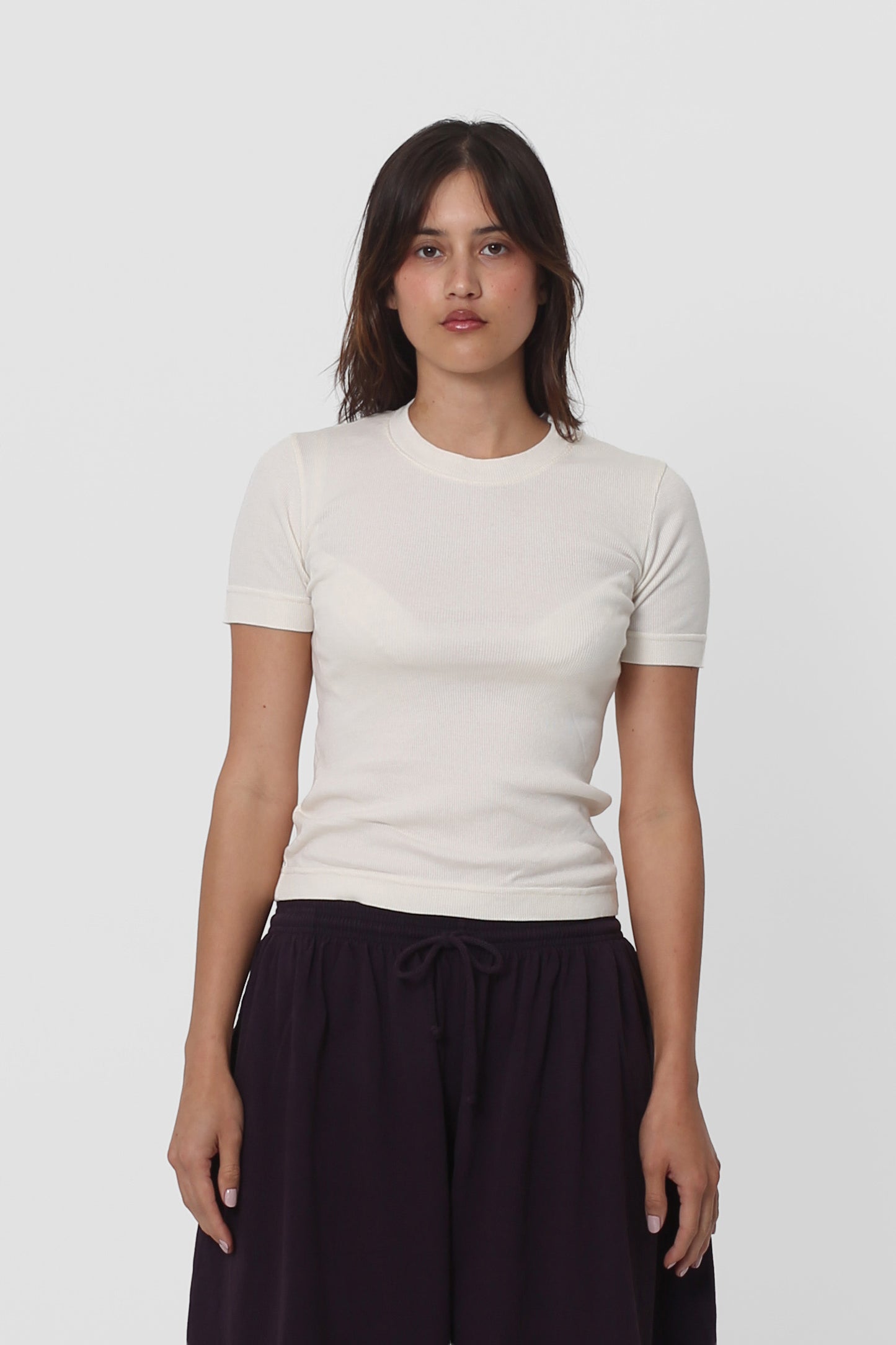 A 5'5" woman in a size S Natural Rib Short Sleeve. Hem rests above her upper hips.