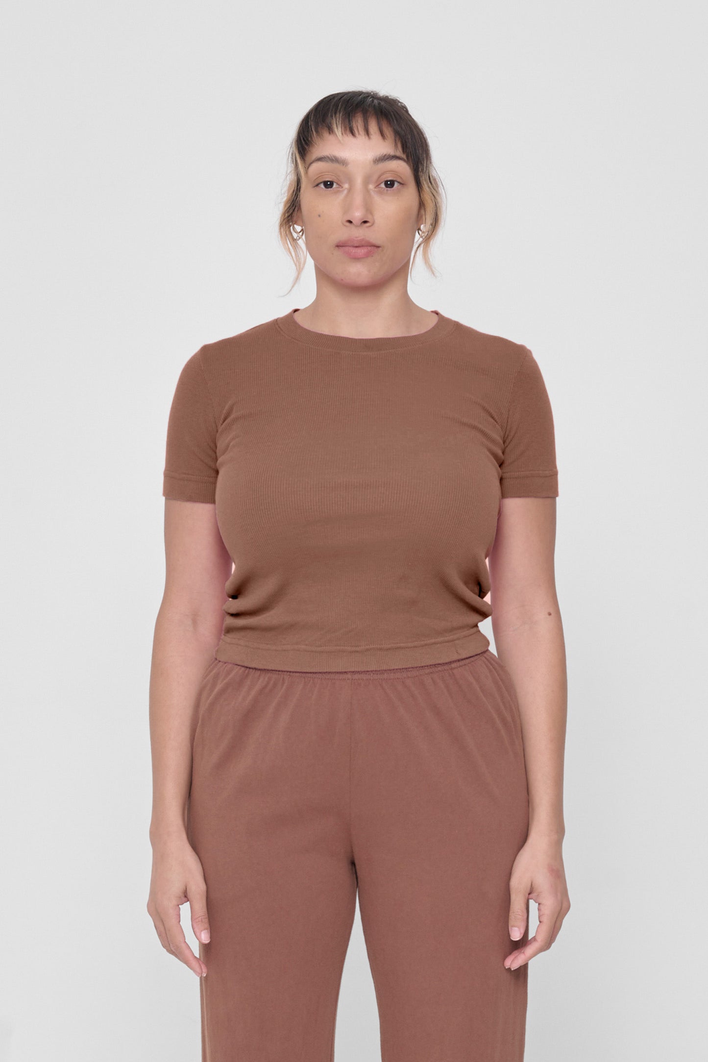 A 5'4" woman in a size S Potting Soil Rib Short Sleeve. Hem rests above her upper hips.