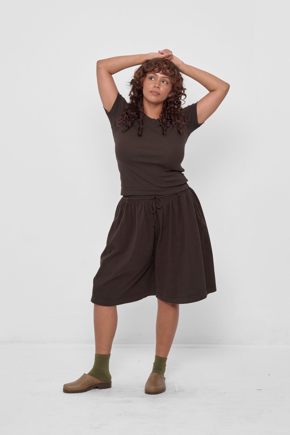 Rib Short Sleeve in Wet Soil - front full body view on model, styled with Wet Soil Long Tubular Shorts, Olive Spring Socks, and Plasticana Mules