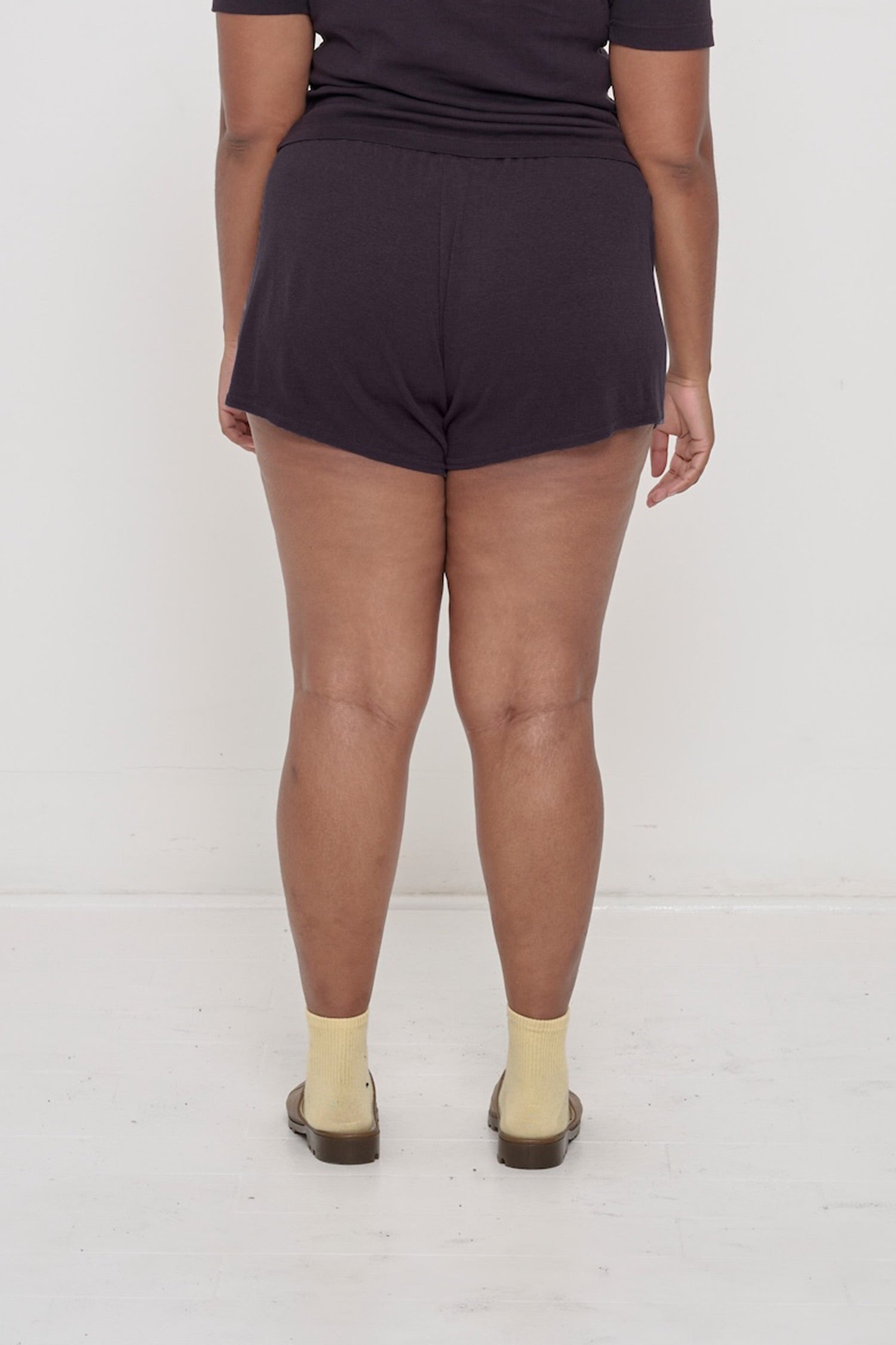 Back view: A model wearing Mulberry Rib Shorts, which have a soft drapey fabric.