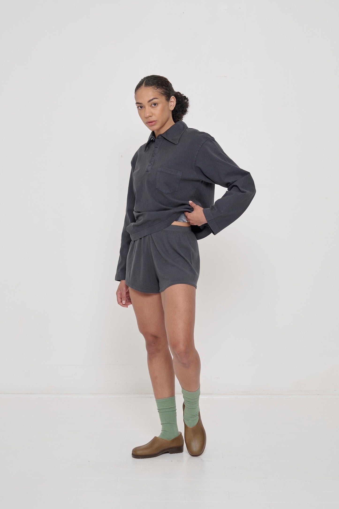 A person wearing Slate Rib Shorts with a Slate Rugby Trash Polo.