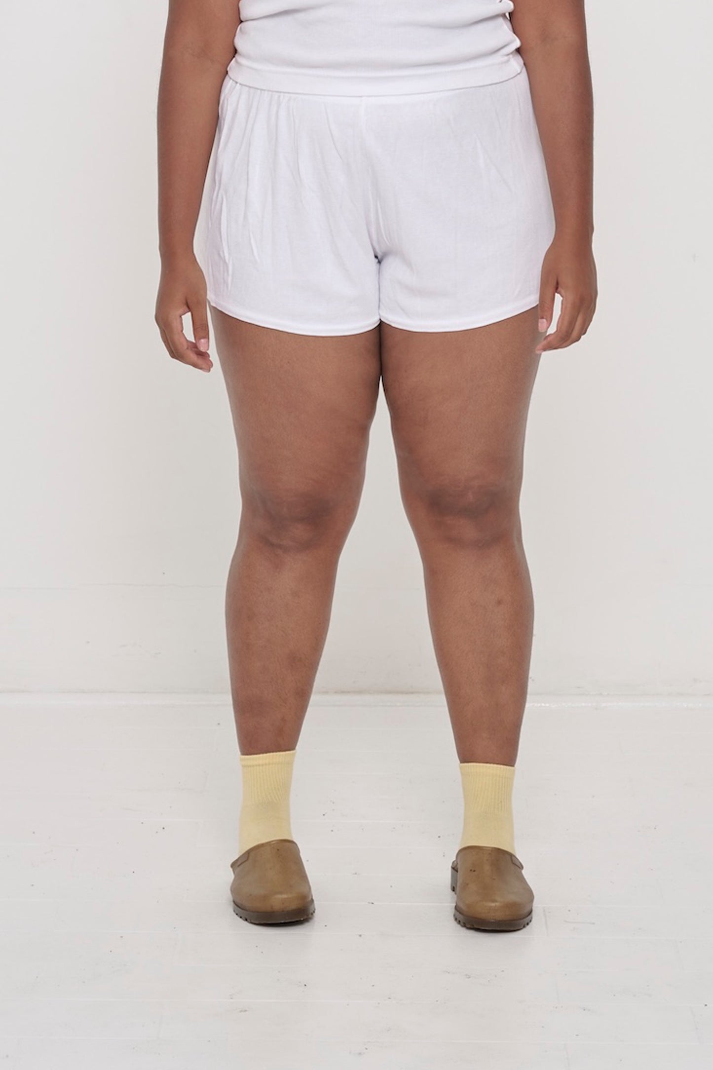 White Rib Shorts on model, waist down. Relaxed fit, upper-thigh length and elastic waist.