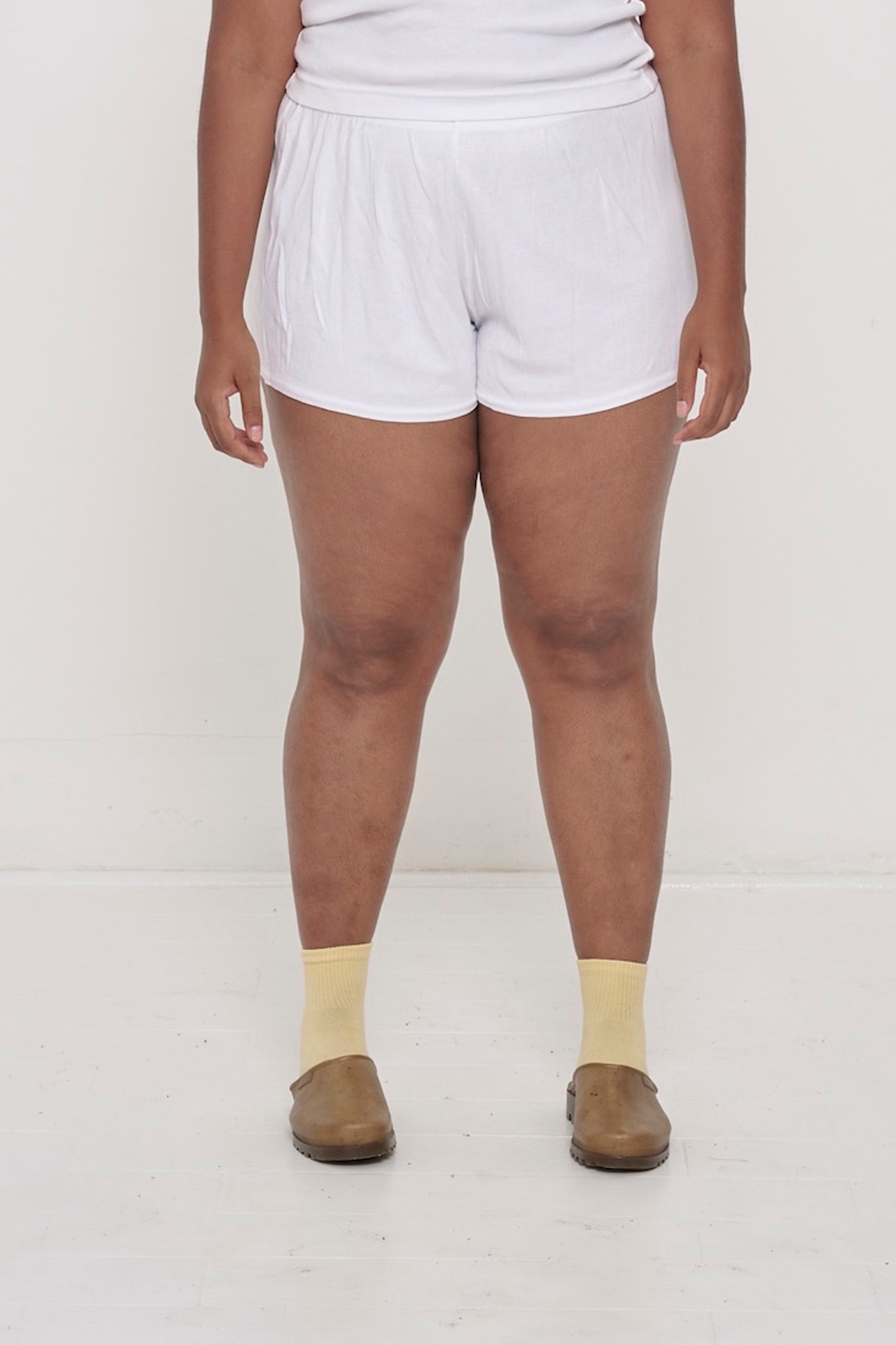 White Rib Shorts on model, waist down. Relaxed fit, upper-thigh length and elastic waist.