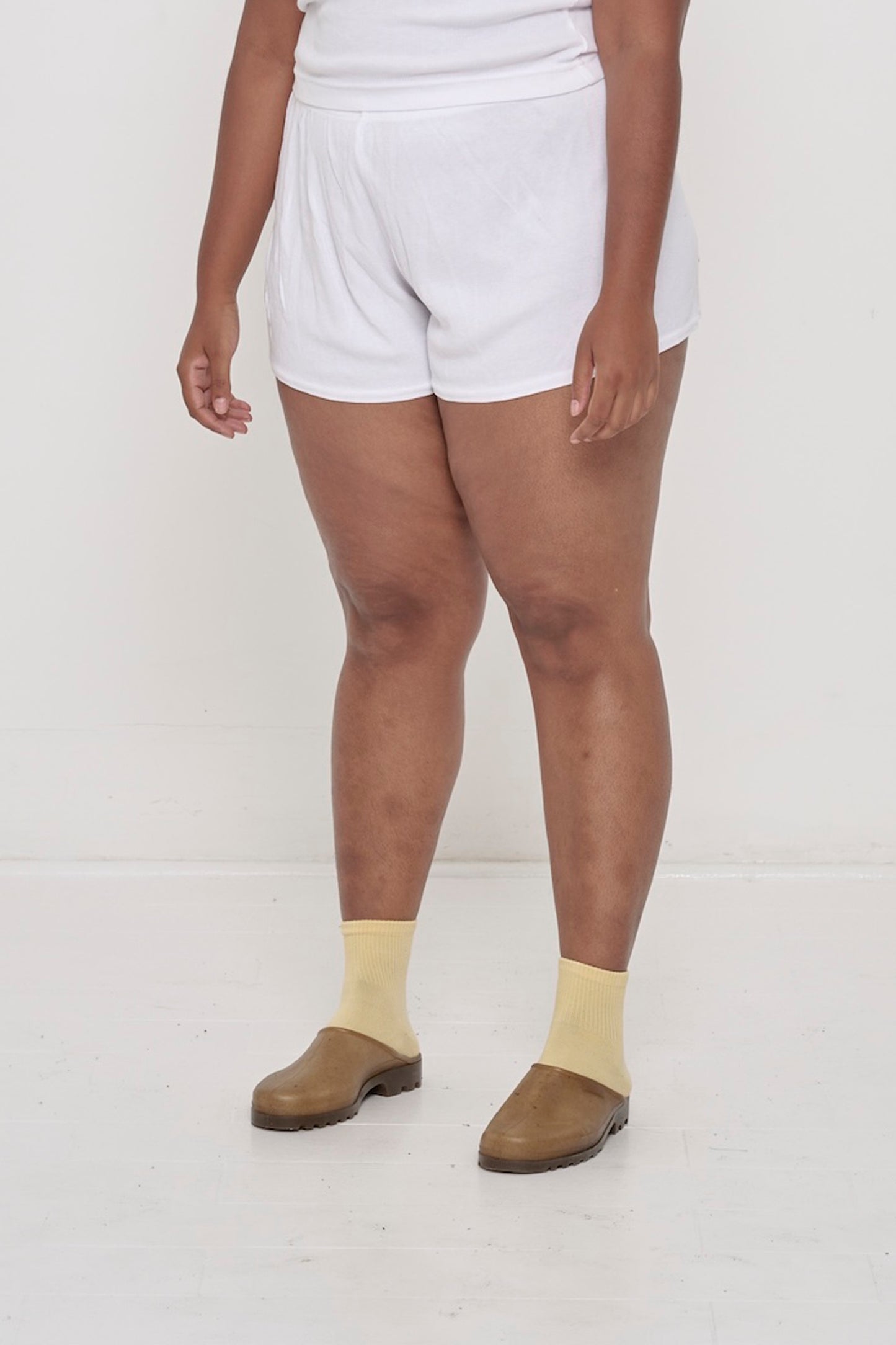A person facing 45-degrees, wearing White Rib Shorts, fitted silhouette.