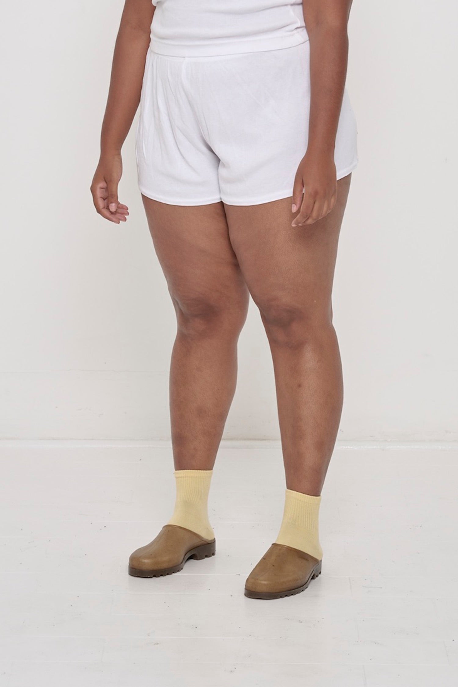 A person facing 45-degrees, wearing White Rib Shorts, fitted silhouette.
