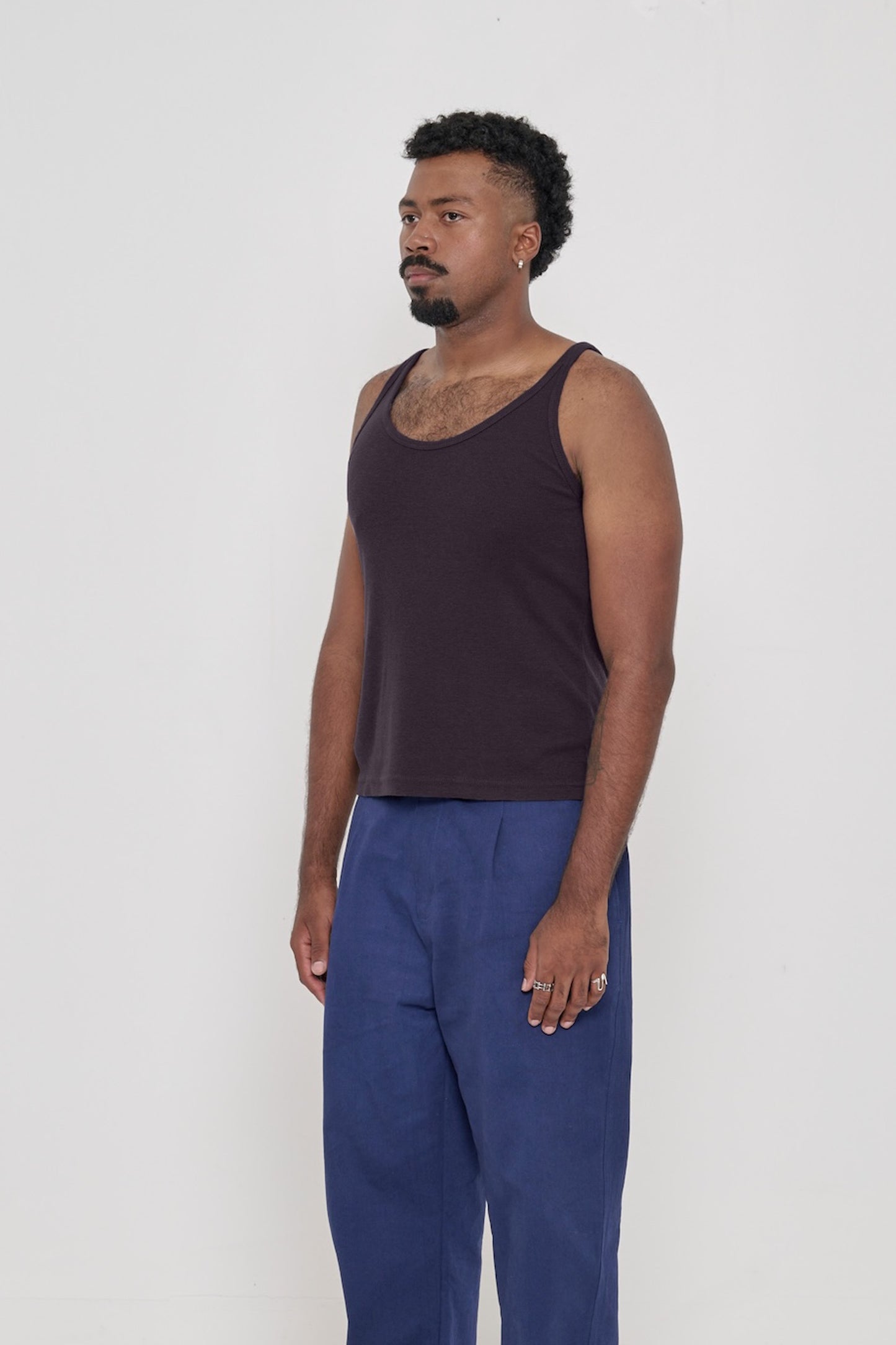 A man facing 45-degrees, wearing a Mulberry Rib Tank, showcasing side seams, heavy hem and straps.