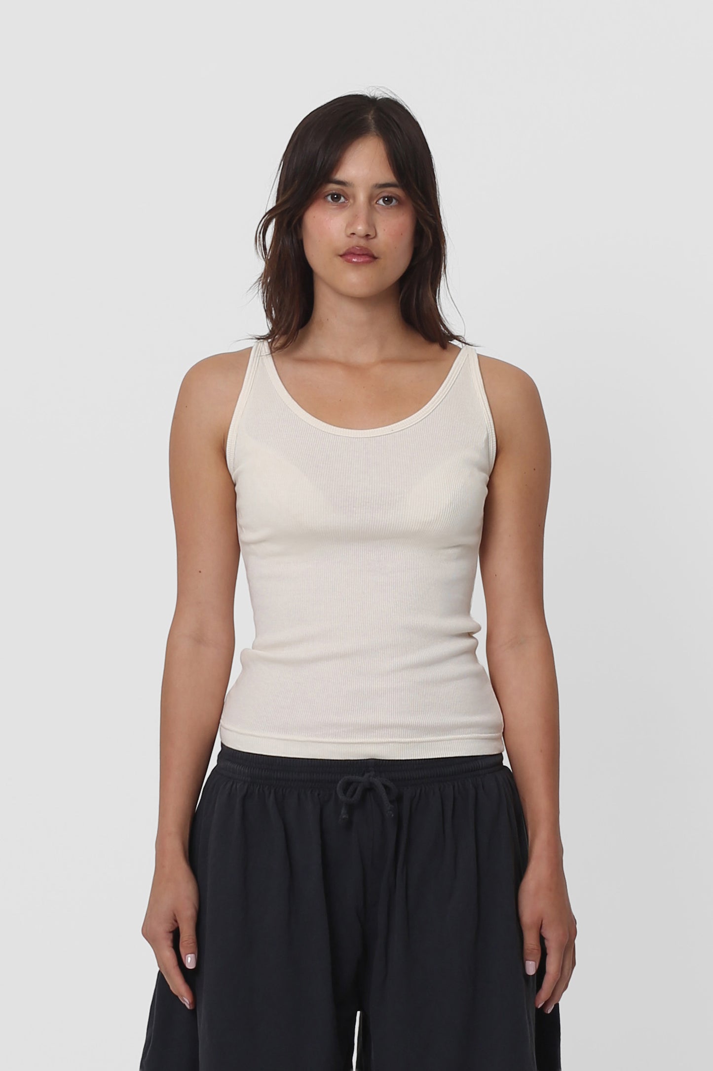 A woman in a Natural Rib Tank, the hem sitting above her Slate Long Tubular Shorts