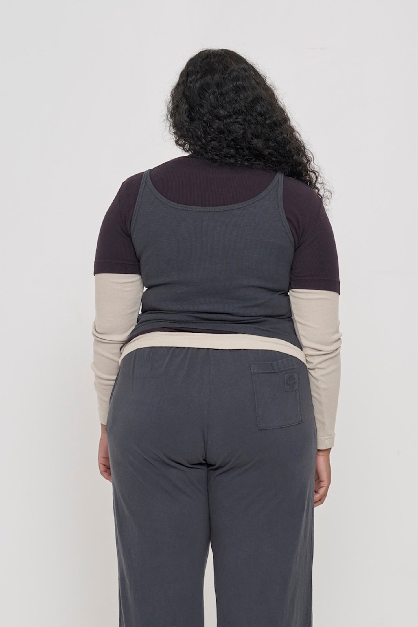 Back view: woman in Slate Rib Tank, fitted upper back, relaxed mid/lower back.