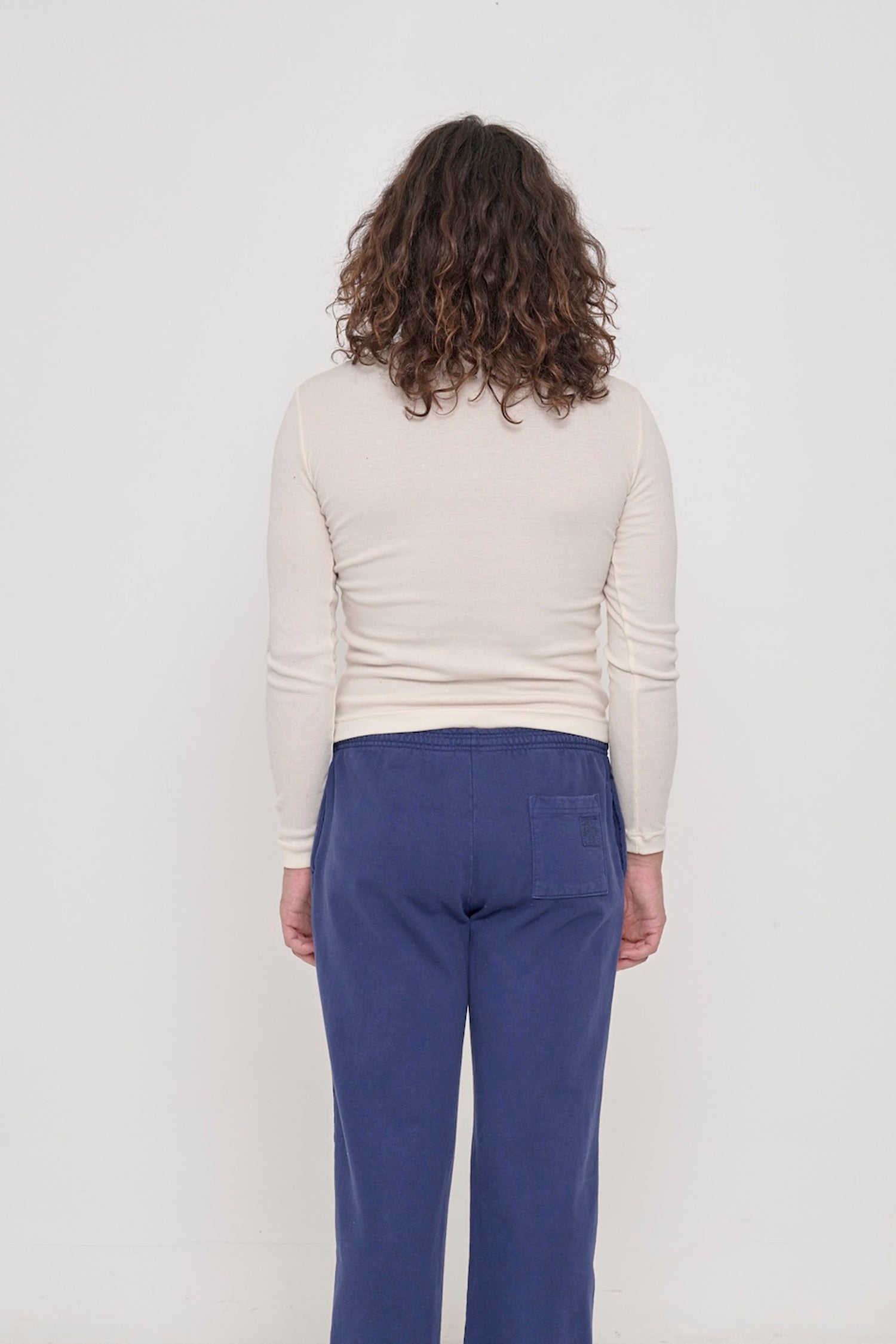 Natural Rib Turtleneck, back view on a person. Fitted through mid to upper back, and looser lower back.