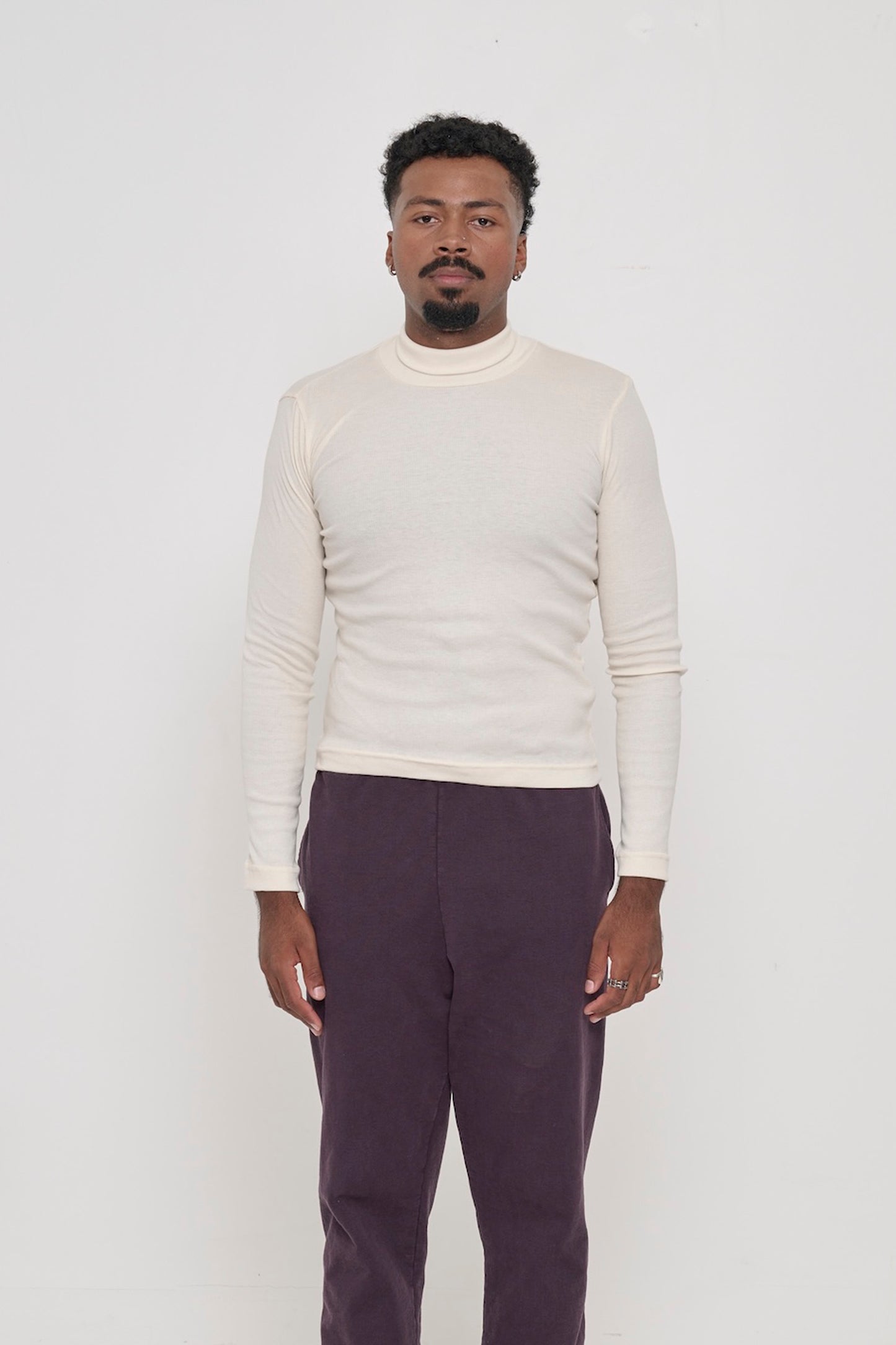 A 6'2" person in a size XL Rib Turtleneck in Natural with collar folded down. Hem rests on his upper hips.
