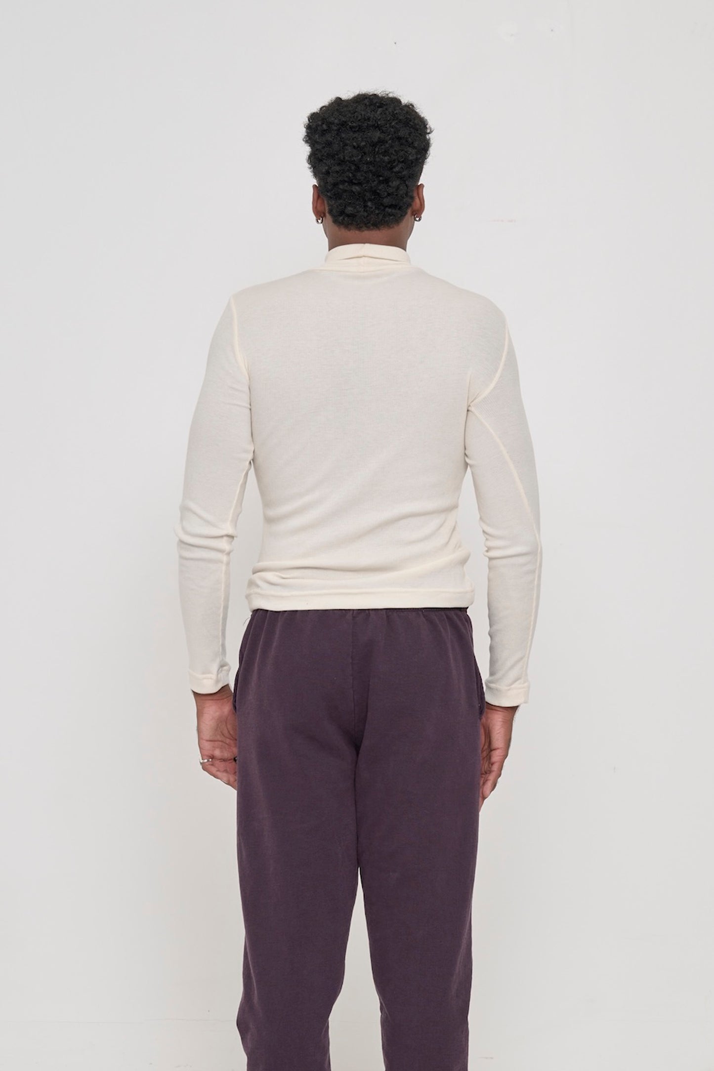 Natural Rib Turtleneck, back view on a person. Fitted through mid to upper back, and looser lower back.