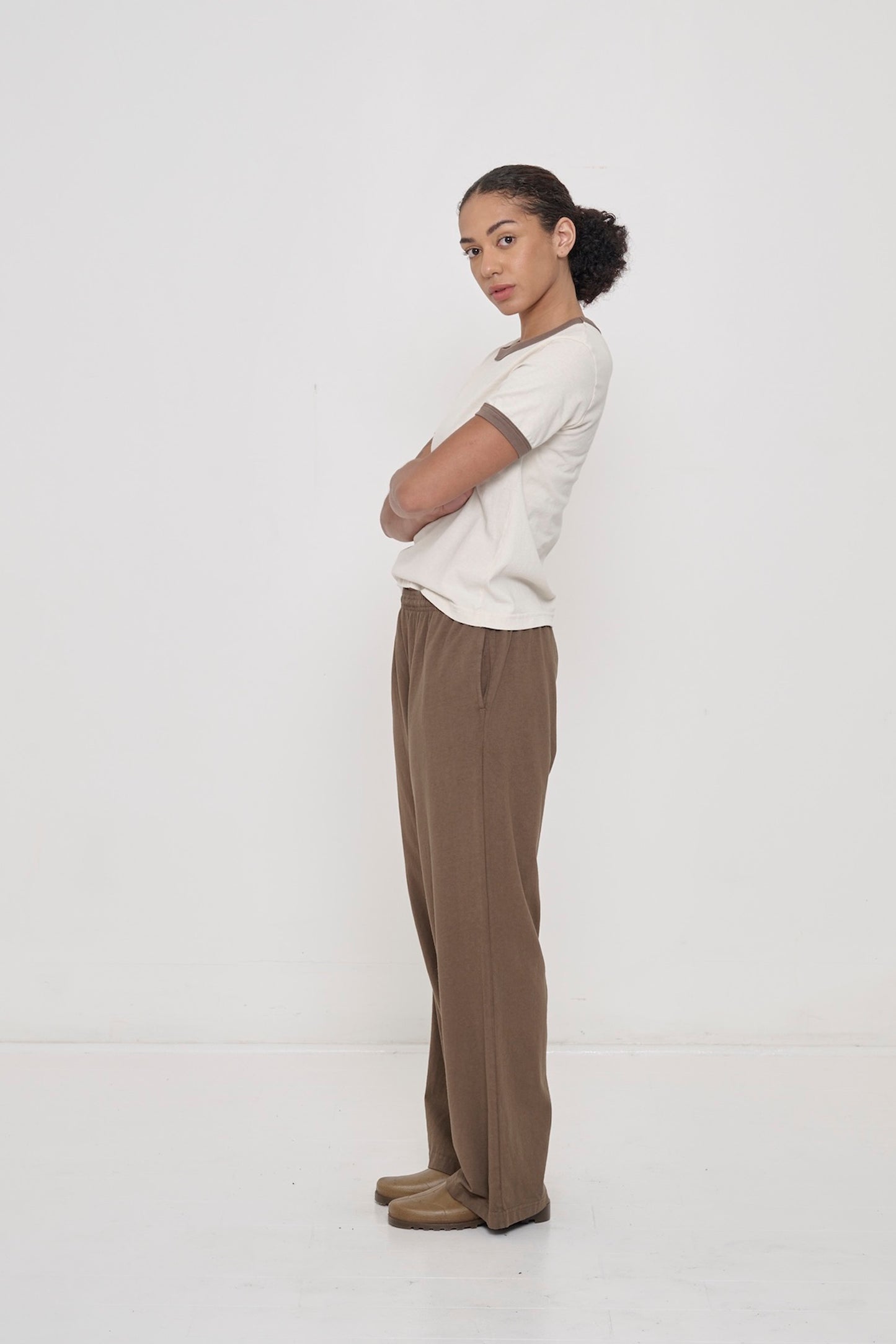 A woman wearing a Dry Soil Ringer Trash Tee with matching Apartment Pants her arms are folded in front of her.