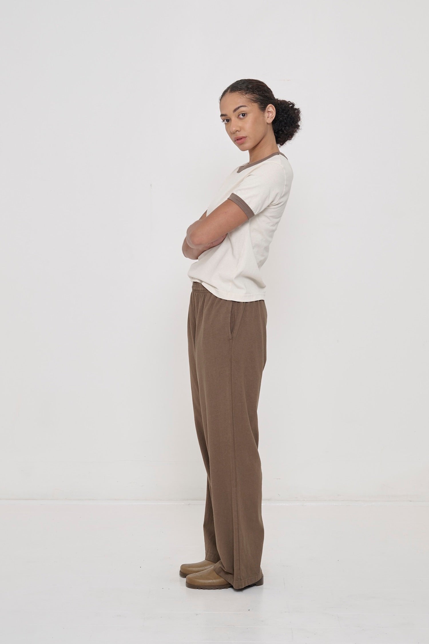 A woman wearing a Dry Soil Ringer Trash Tee with matching Apartment Pants her arms are folded in front of her.