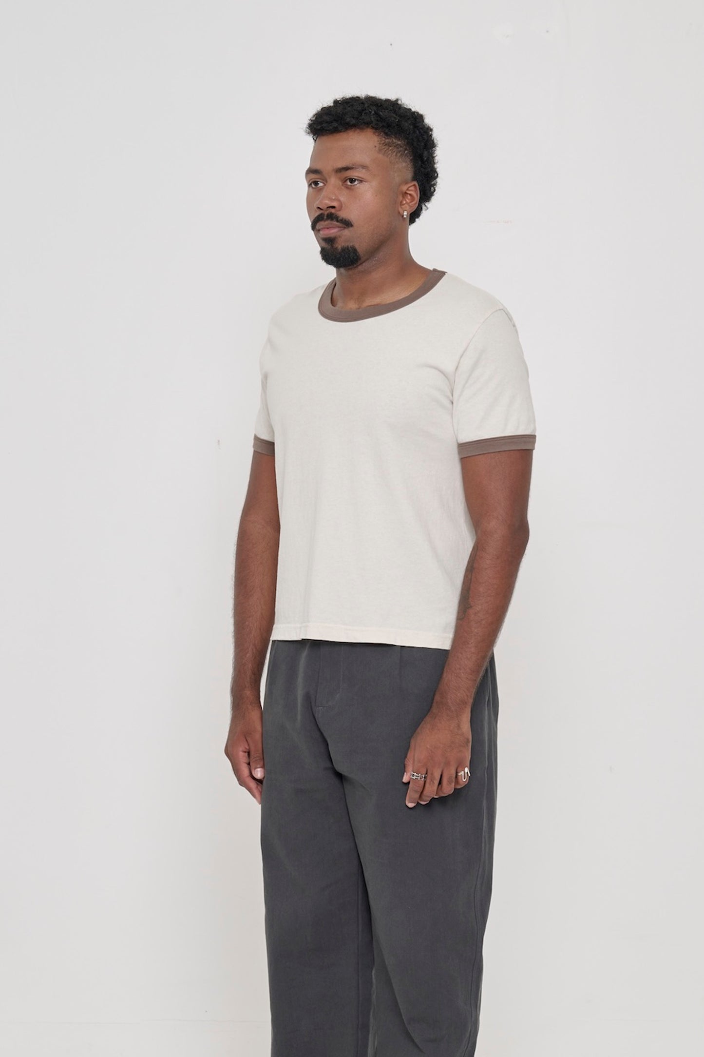 A person turned 45-degrees from the front, wearing a Dry Soil Ringer Trash Tee, showing the side seams and slim fit.